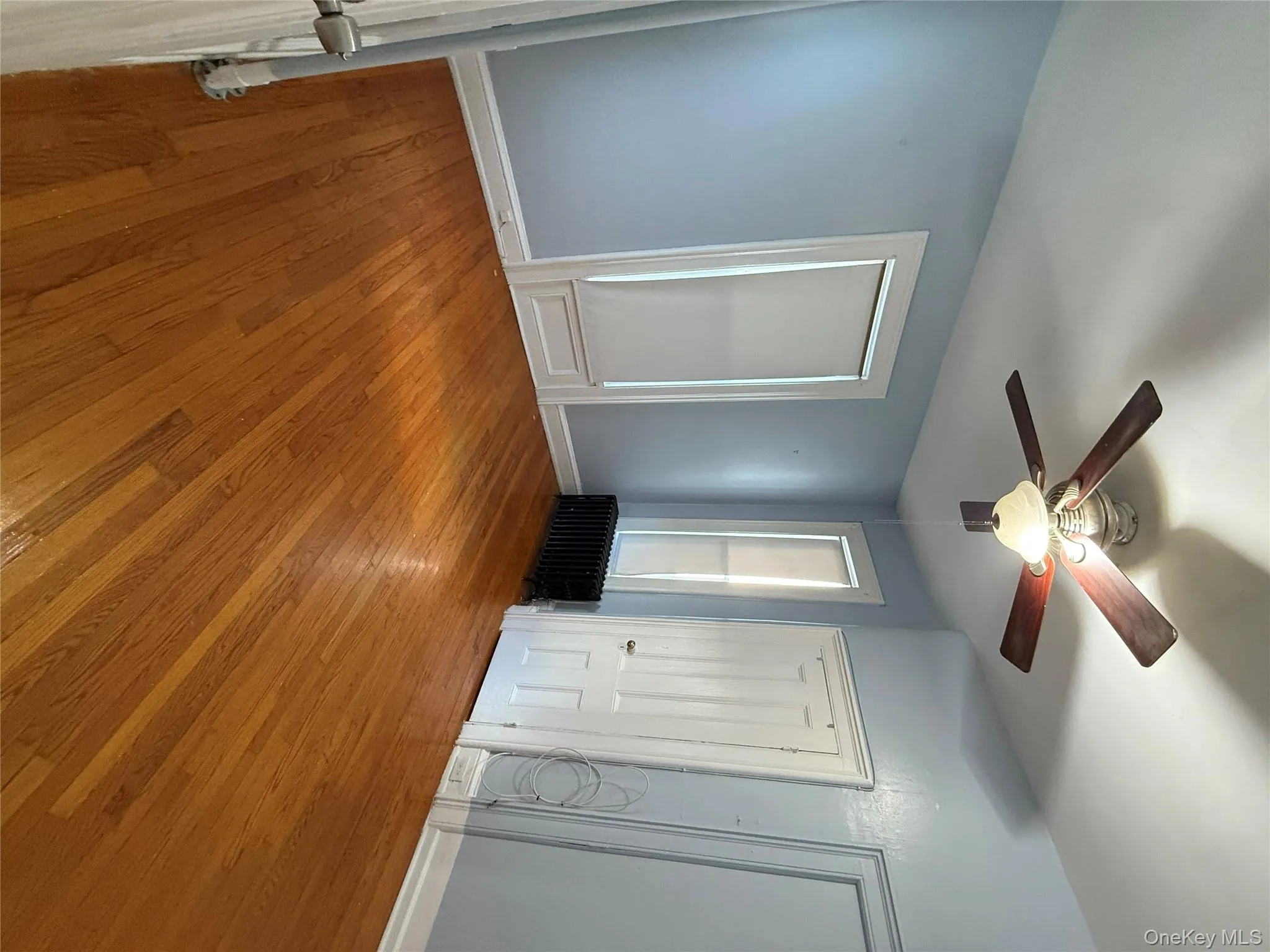 Unfurnished bedroom featuring light wood finished floors, radiator, a ceiling fan, and multiple closets Unfurnished bedroom featuring light wood finished floors, radiator, a ceiling fan, and multiple closets