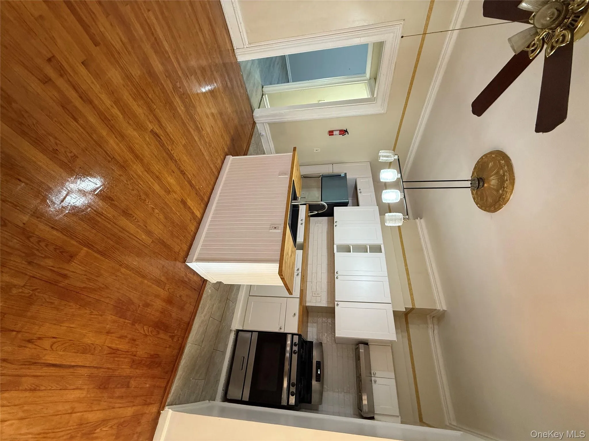 Kitchen featuring decorative backsplash, range, white cabinetry, ornamental molding, and light wood-style flooring Kitchen featuring decorative backsplash, range, white cabinetry, ornamental molding, and light wood-style flooring