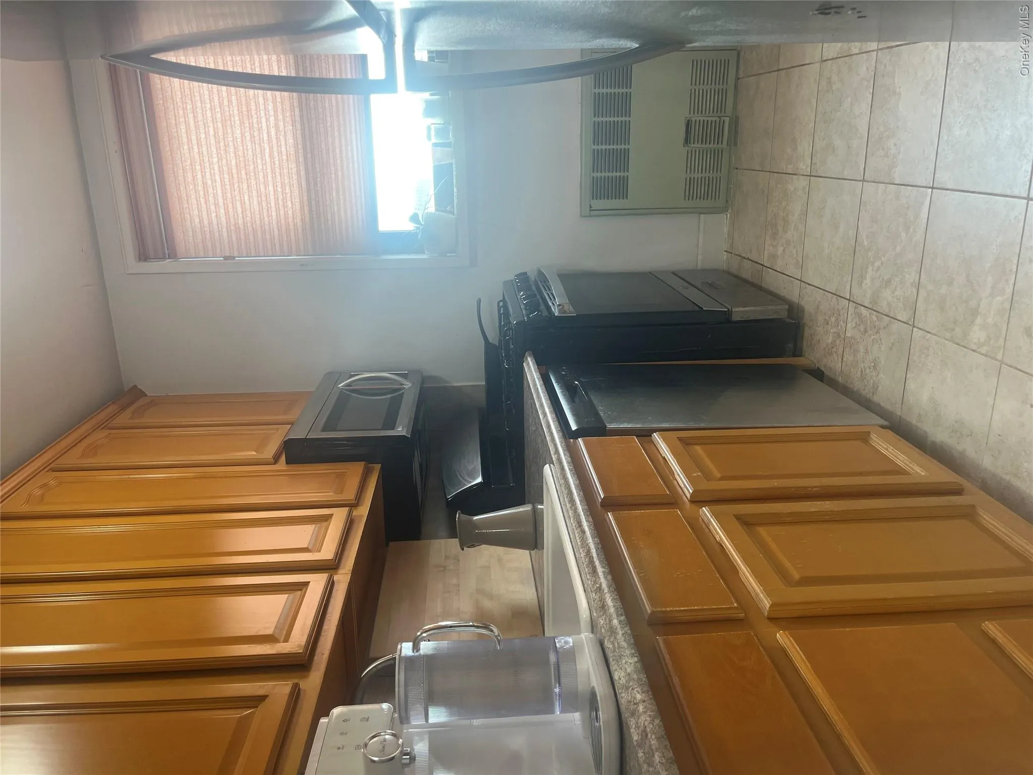 Kitchen featuring brown cabinetry, range, radiator, dishwasher, and light tile patterned flooring Kitchen featuring brown cabinetry, range, radiator, dishwasher, and light tile patterned flooring
