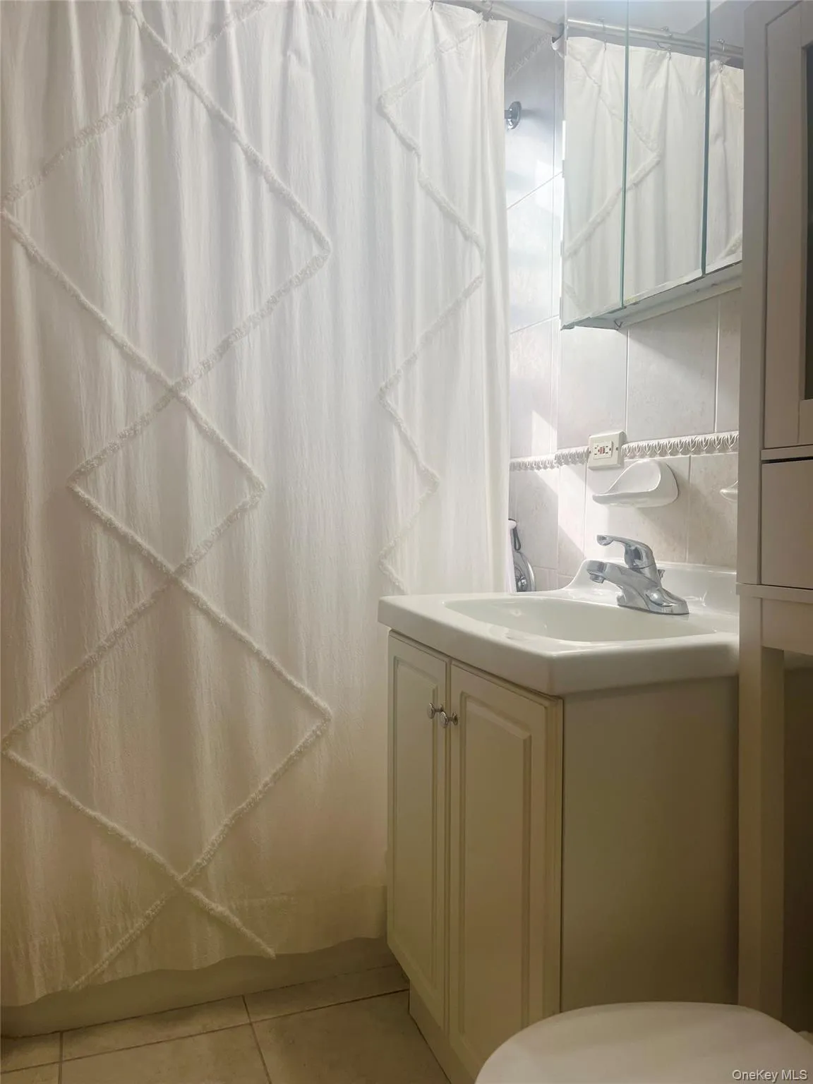 Bathroom with a shower with curtain, tasteful backsplash, vanity, and light tile patterned floors Bathroom with a shower with curtain, tasteful backsplash, vanity, and light tile patterned floors