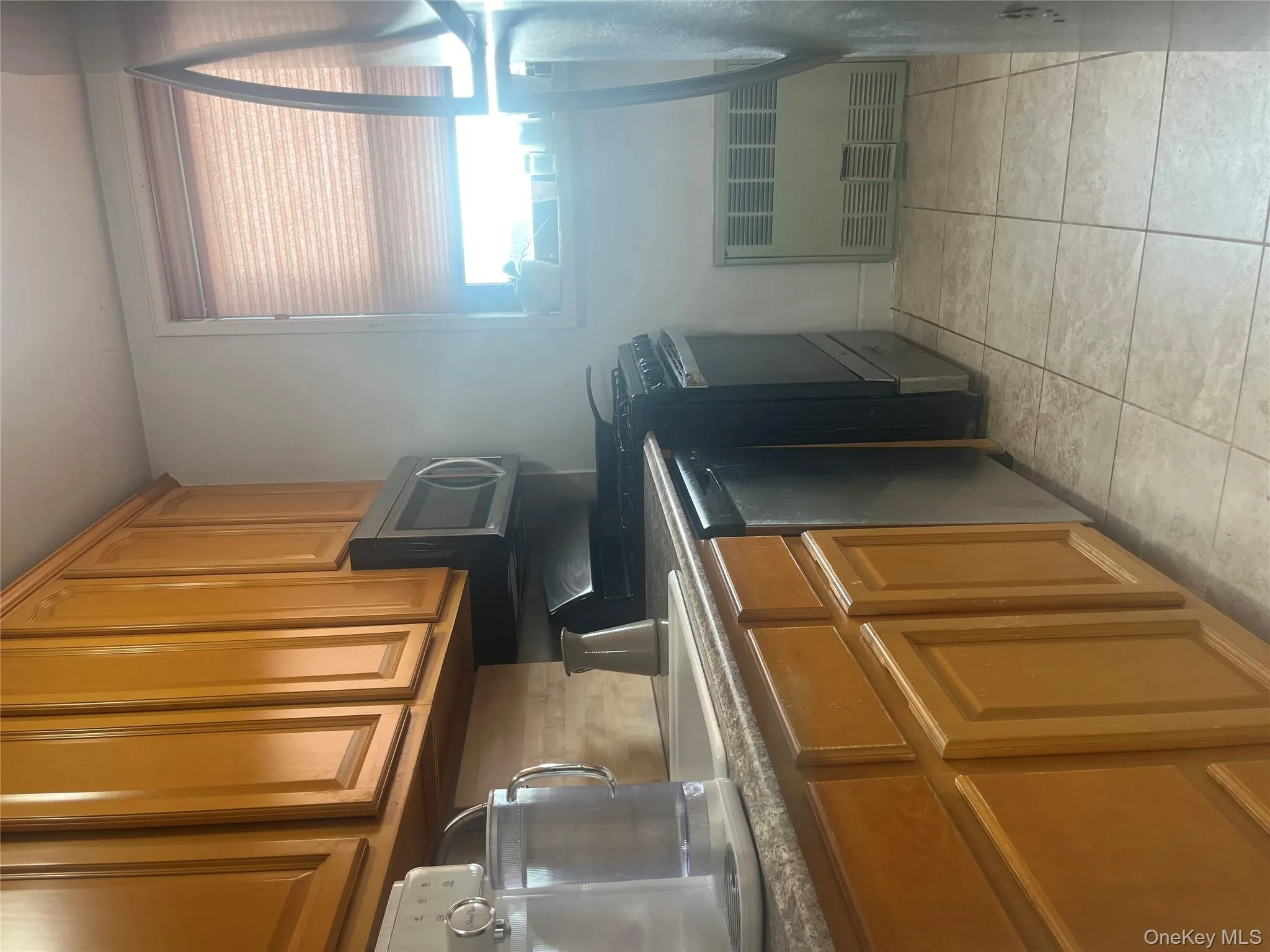 Kitchen featuring brown cabinetry, range, radiator, dishwasher, and light tile patterned flooring Kitchen featuring brown cabinetry, range, radiator, dishwasher, and light tile patterned flooring