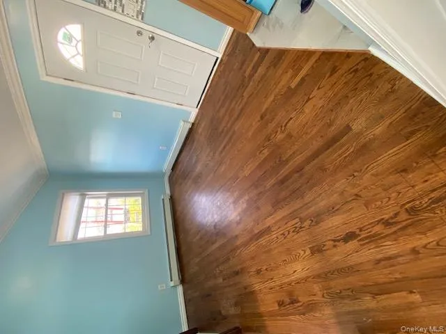 Foyer entrance featuring dark wood-style flooring, crown molding, a baseboard radiator, and vaulted ceiling Foyer entrance featuring dark wood-style flooring, crown molding, a baseboard radiator, and vaulted ceiling