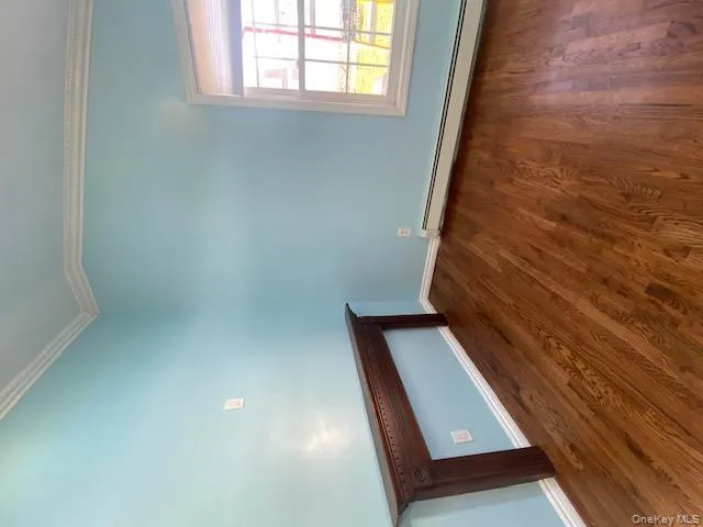 Empty room featuring ornamental molding, baseboard heating, and dark wood-style flooring Empty room featuring ornamental molding, baseboard heating, and dark wood-style flooring