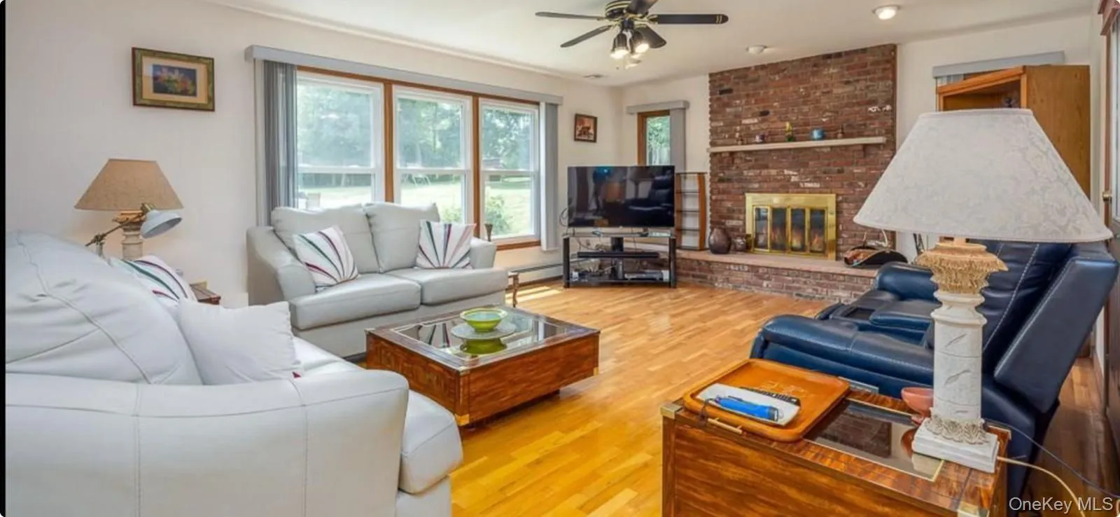Living room featuring light wood finished floors, a fireplace, and ceiling fan Living room featuring light wood finished floors, a fireplace, and ceiling fan