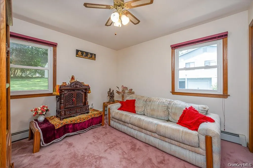 Living room featuring carpet, a baseboard heating unit, and a ceiling fan Living room featuring carpet, a baseboard heating unit, and a ceiling fan