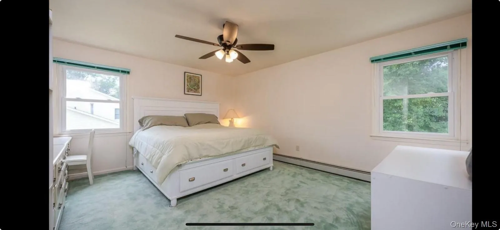 Bedroom featuring a baseboard heating unit, light colored carpet, and ceiling fan Bedroom featuring a baseboard heating unit, light colored carpet, and ceiling fan