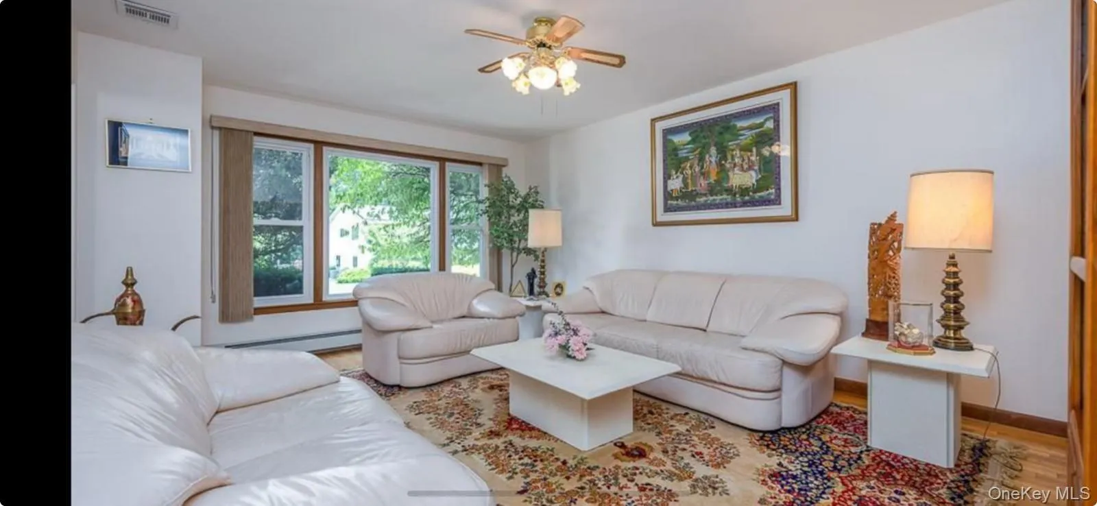 Living room with wood finished floors, a baseboard heating unit, and ceiling fan Living room with wood finished floors, a baseboard heating unit, and ceiling fan