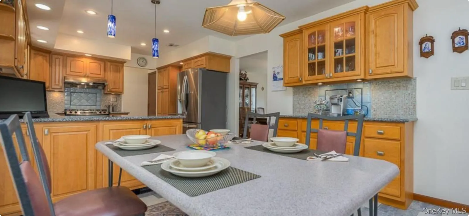 Kitchen featuring tasteful backsplash, a breakfast bar, stainless steel appliances, recessed lighting, and glass insert cabinets Kitchen featuring tasteful backsplash, a breakfast bar, stainless steel appliances, recessed lighting, and glass insert cabinets