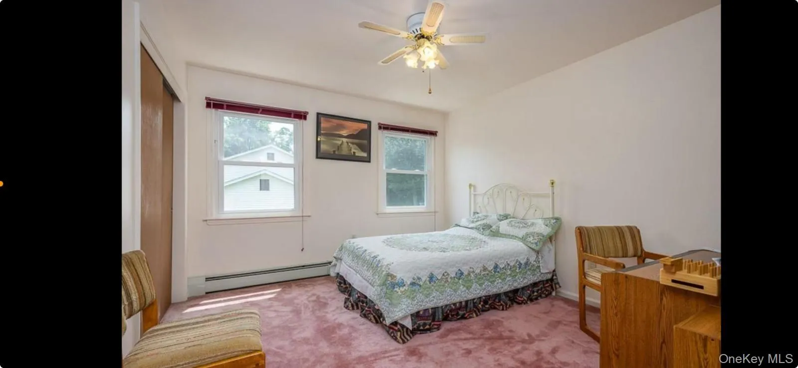 Carpeted bedroom with a baseboard radiator and ceiling fan Carpeted bedroom with a baseboard radiator and ceiling fan