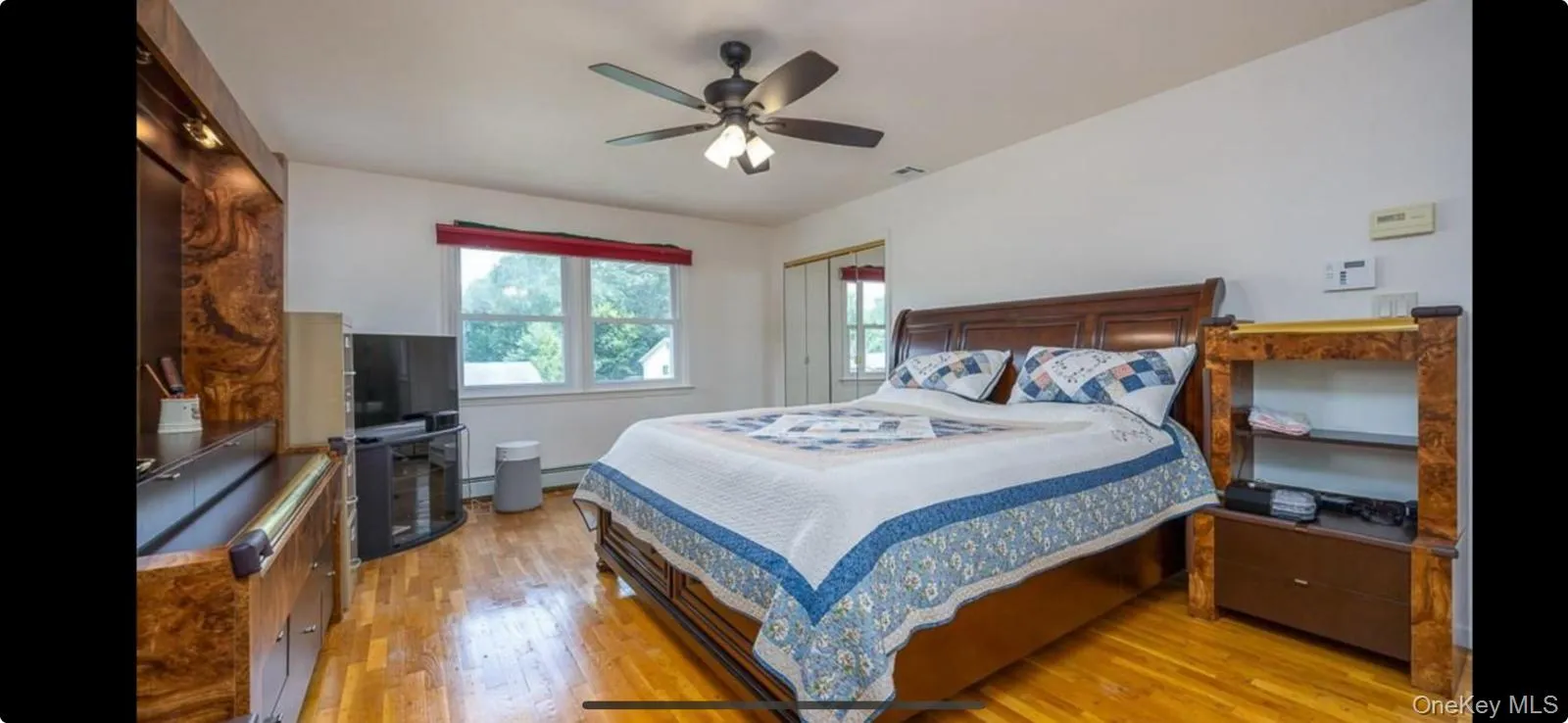 Bedroom with light wood-style floors, ceiling fan, and baseboard heating Bedroom with light wood-style floors, ceiling fan, and baseboard heating