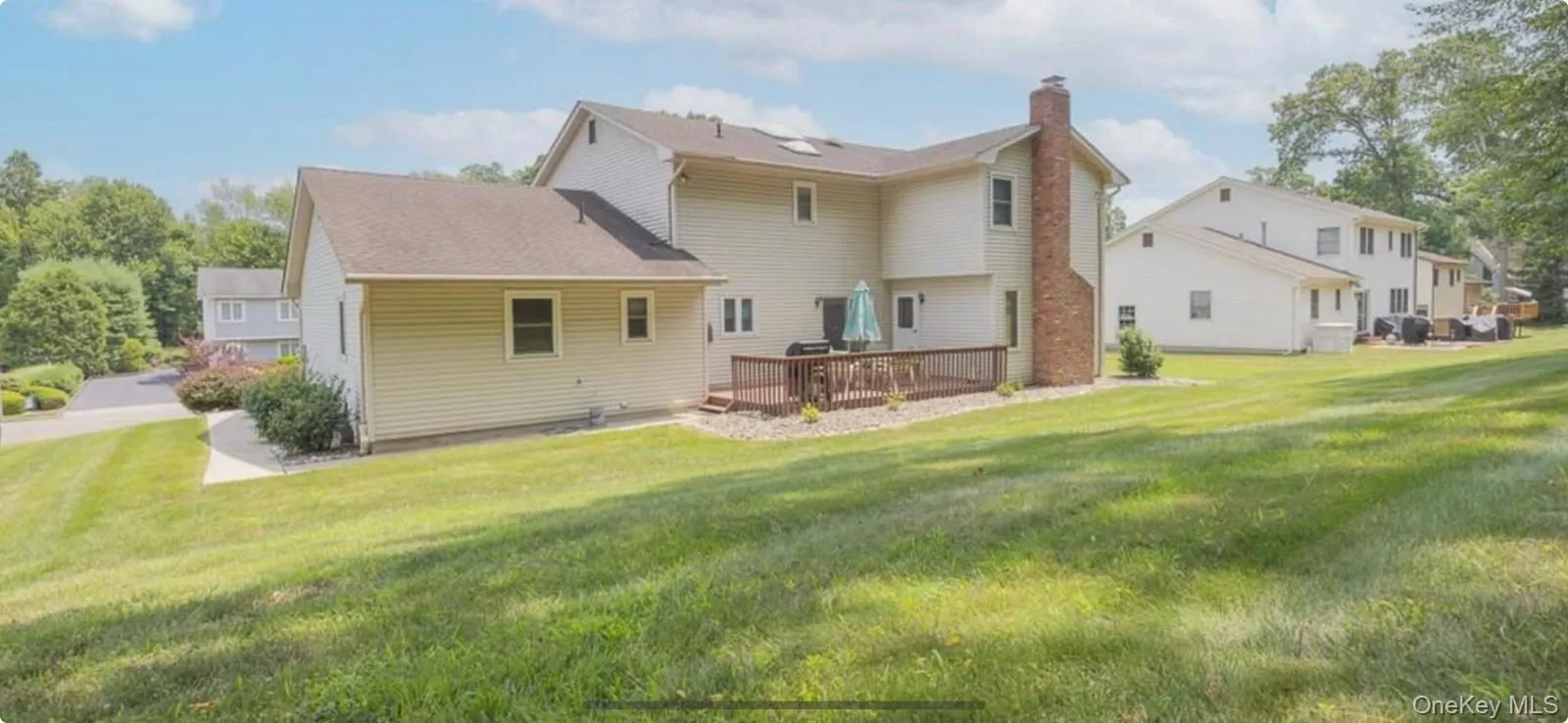 Back of house featuring a wooden deck, a yard, and a chimney Back of house featuring a wooden deck, a yard, and a chimney