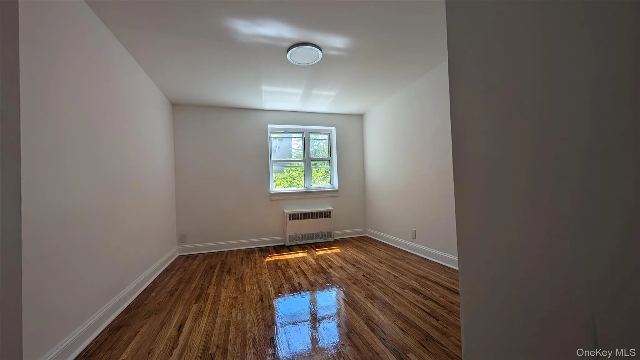 Empty room featuring dark wood-style flooring and radiator Empty room featuring dark wood-style flooring and radiator