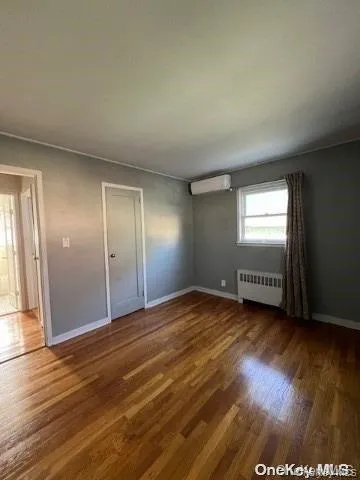 Unfurnished bedroom featuring wood finished floors, radiator, and crown molding Unfurnished bedroom featuring wood finished floors, radiator, and crown molding