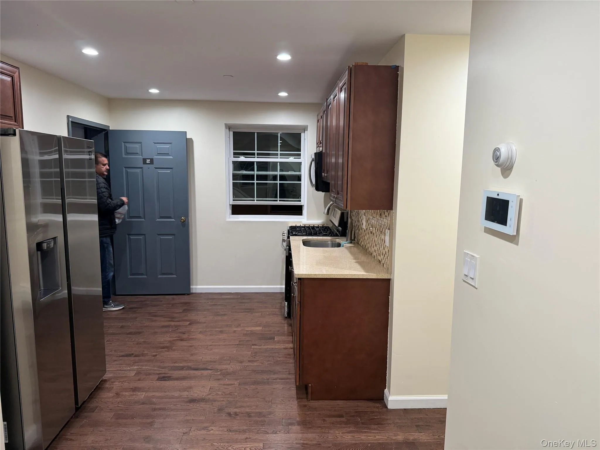 Kitchen featuring appliances with stainless steel finishes, light stone counters, dark wood-style flooring, dark brown cabinetry, and recessed lighting Kitchen featuring appliances with stainless steel finishes, light stone counters, dark wood-style flooring, dark brown cabinetry, and recessed lighting