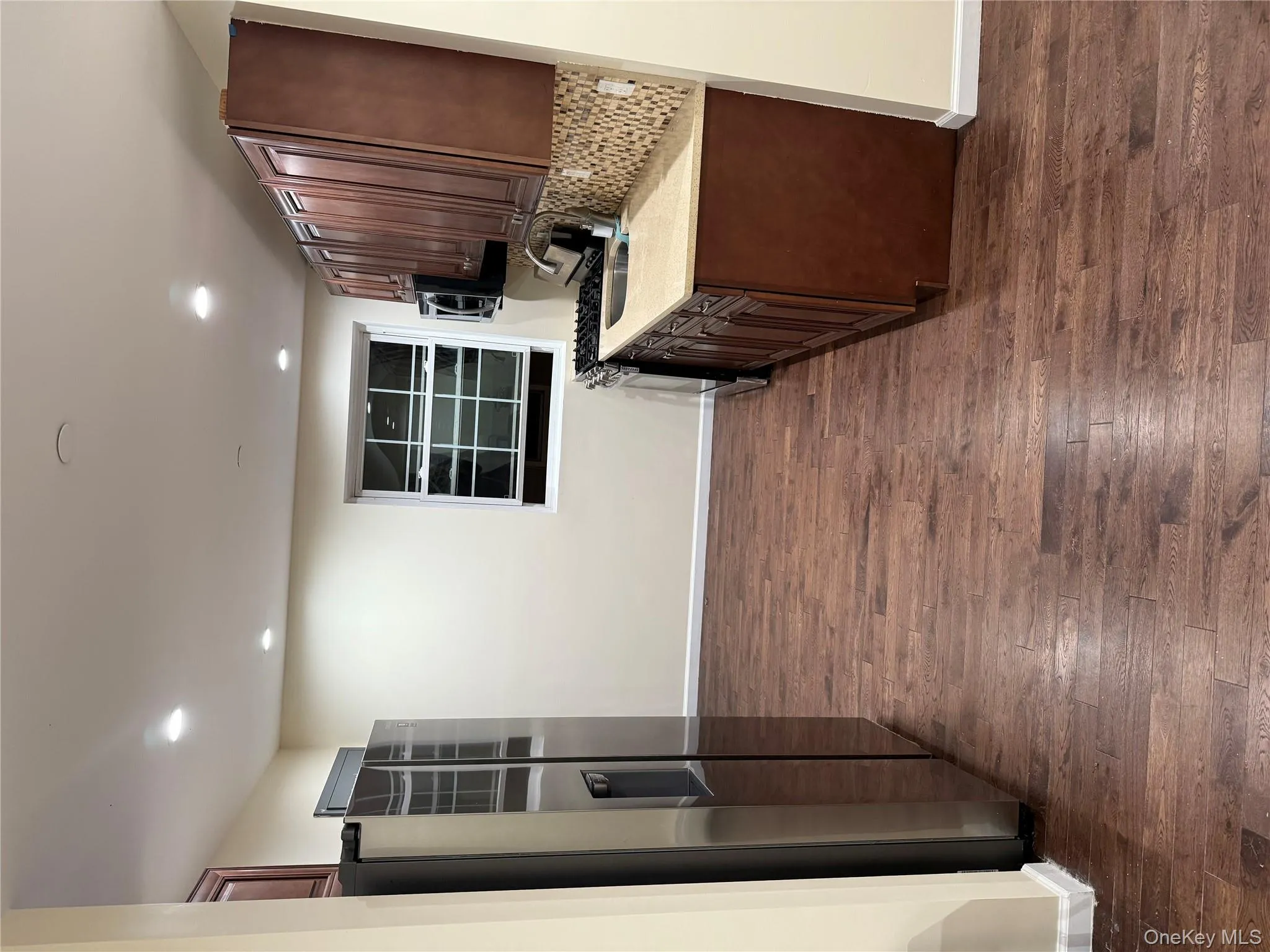 Kitchen featuring fridge, dark wood-style flooring, stove, recessed lighting, and backsplash Kitchen featuring fridge, dark wood-style flooring, stove, recessed lighting, and backsplash