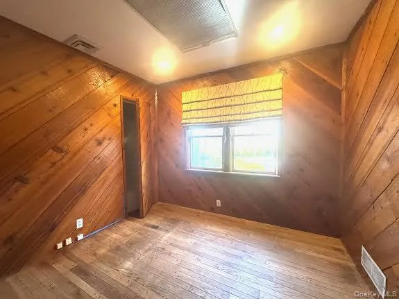 Spare room with wooden walls and hardwood / wood-style floors Spare room with wooden walls and hardwood / wood-style floors