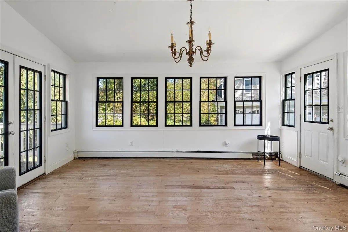 SunRoom featuring a chandelier, light wood-type flooring, french doors, baseboard heating, and vaulted ceiling SunRoom featuring a chandelier, light wood-type flooring, french doors, baseboard heating, and vaulted ceiling