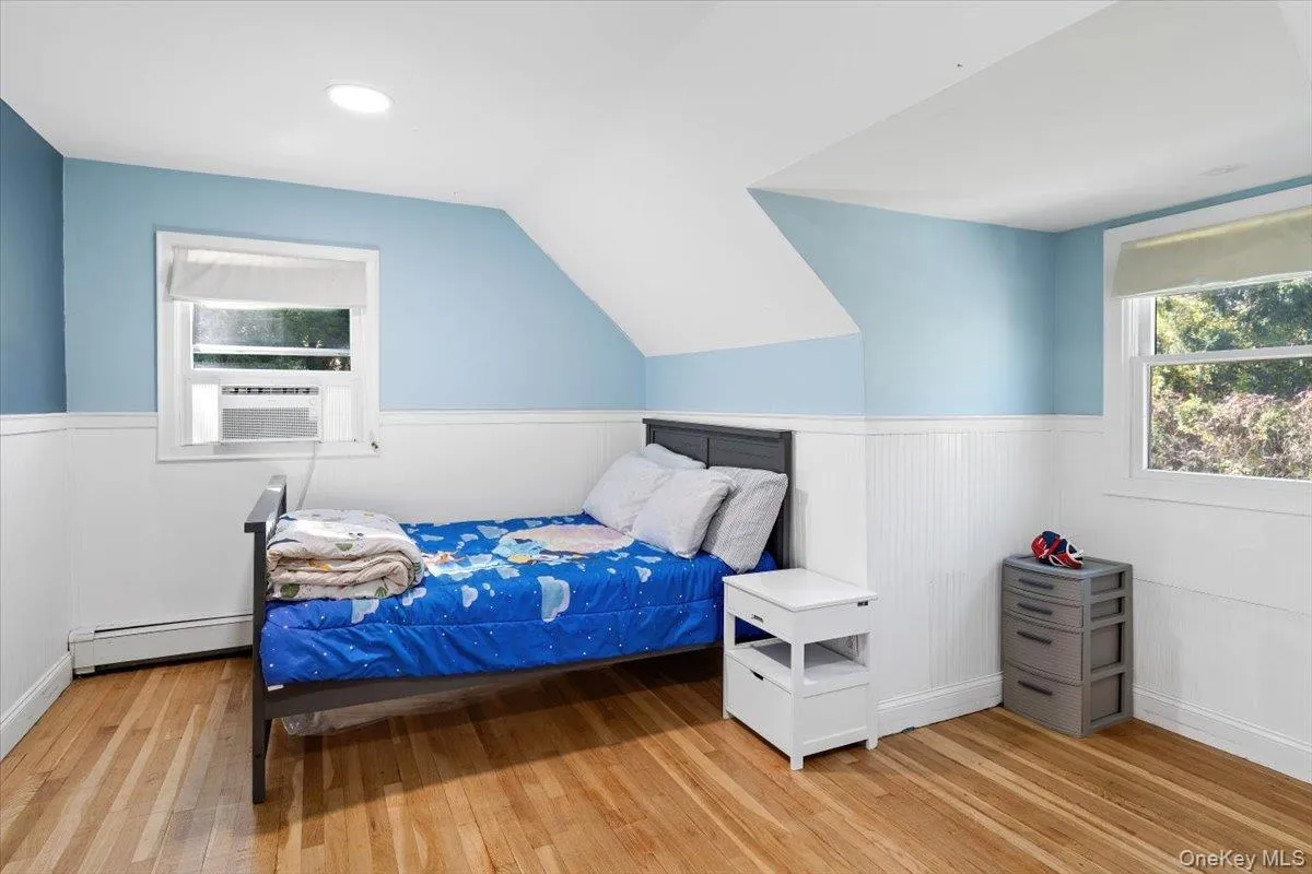3rd Bedroom with wainscoting, light wood finished floors, baseboard heating, and lofted ceiling 3rd Bedroom with wainscoting, light wood finished floors, baseboard heating, and lofted ceiling