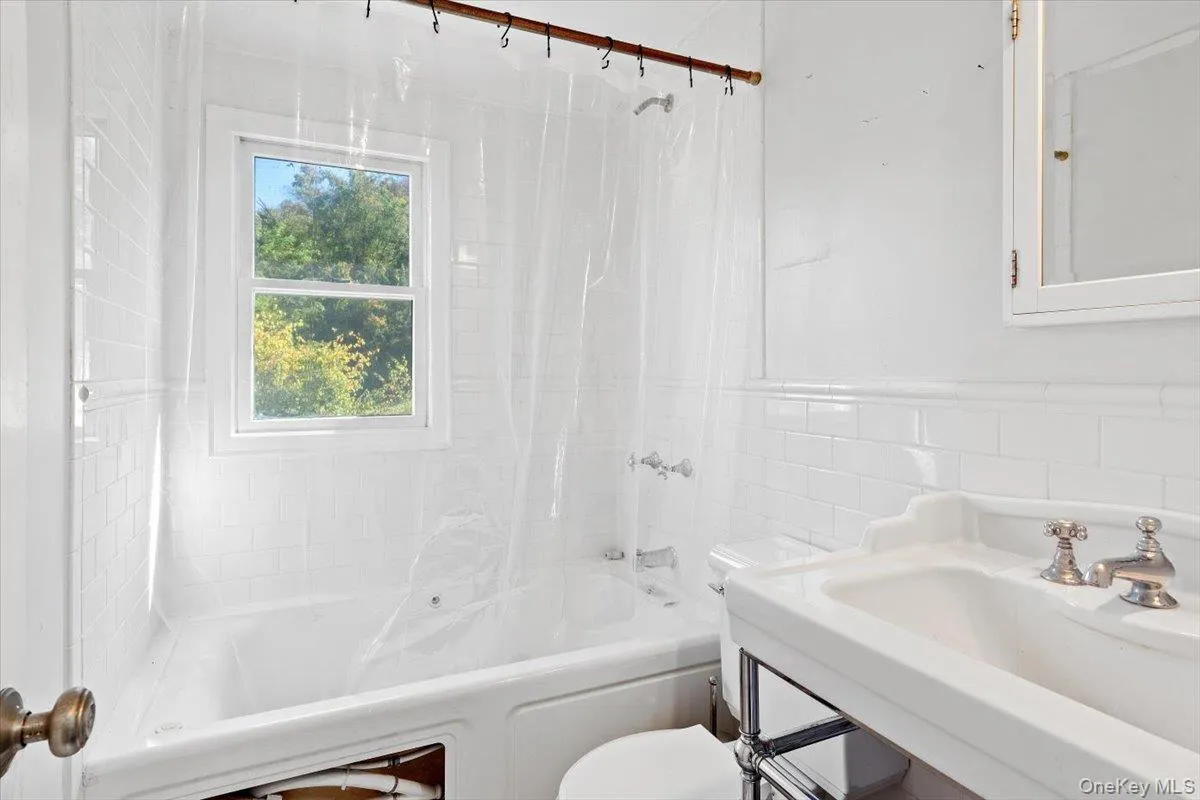 Bathroom featuring tile walls and shower / bath combination with curtain Bathroom featuring tile walls and shower / bath combination with curtain