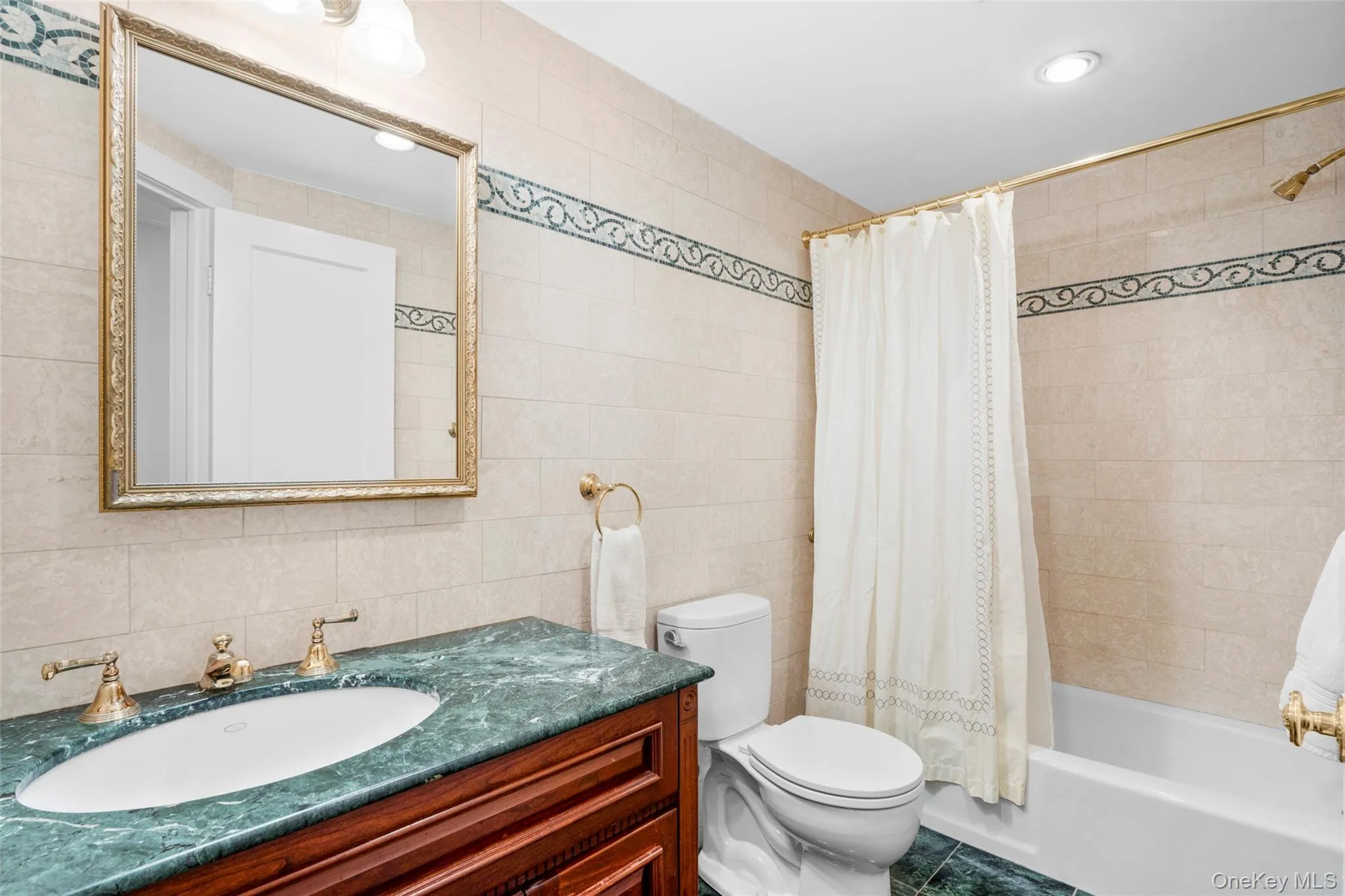 Bathroom with tile walls, vanity, shower / tub combo, recessed lighting, and backsplash Bathroom with tile walls, vanity, shower / tub combo, recessed lighting, and backsplash
