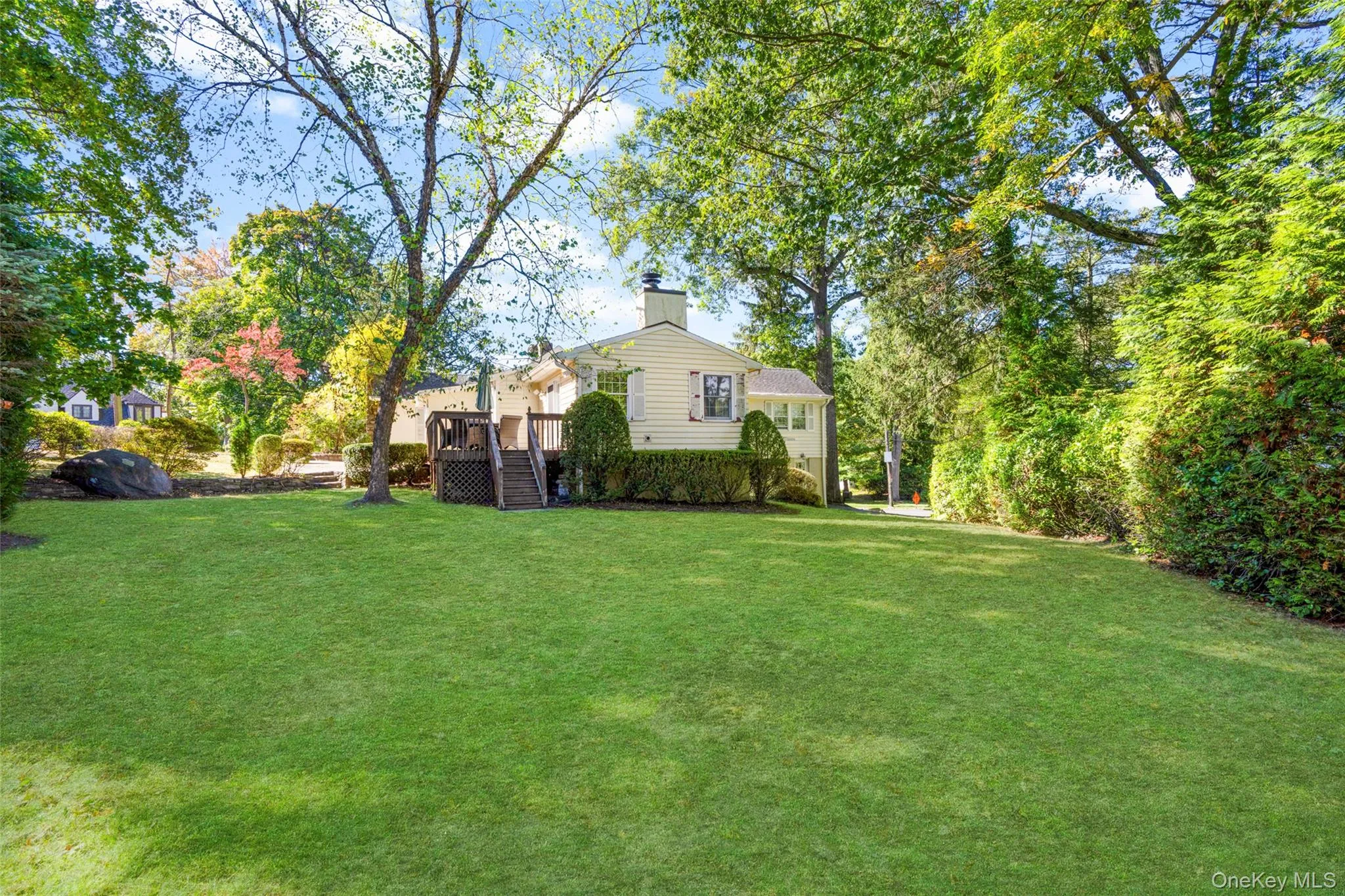 View of green lawn featuring a wooden deck View of green lawn featuring a wooden deck