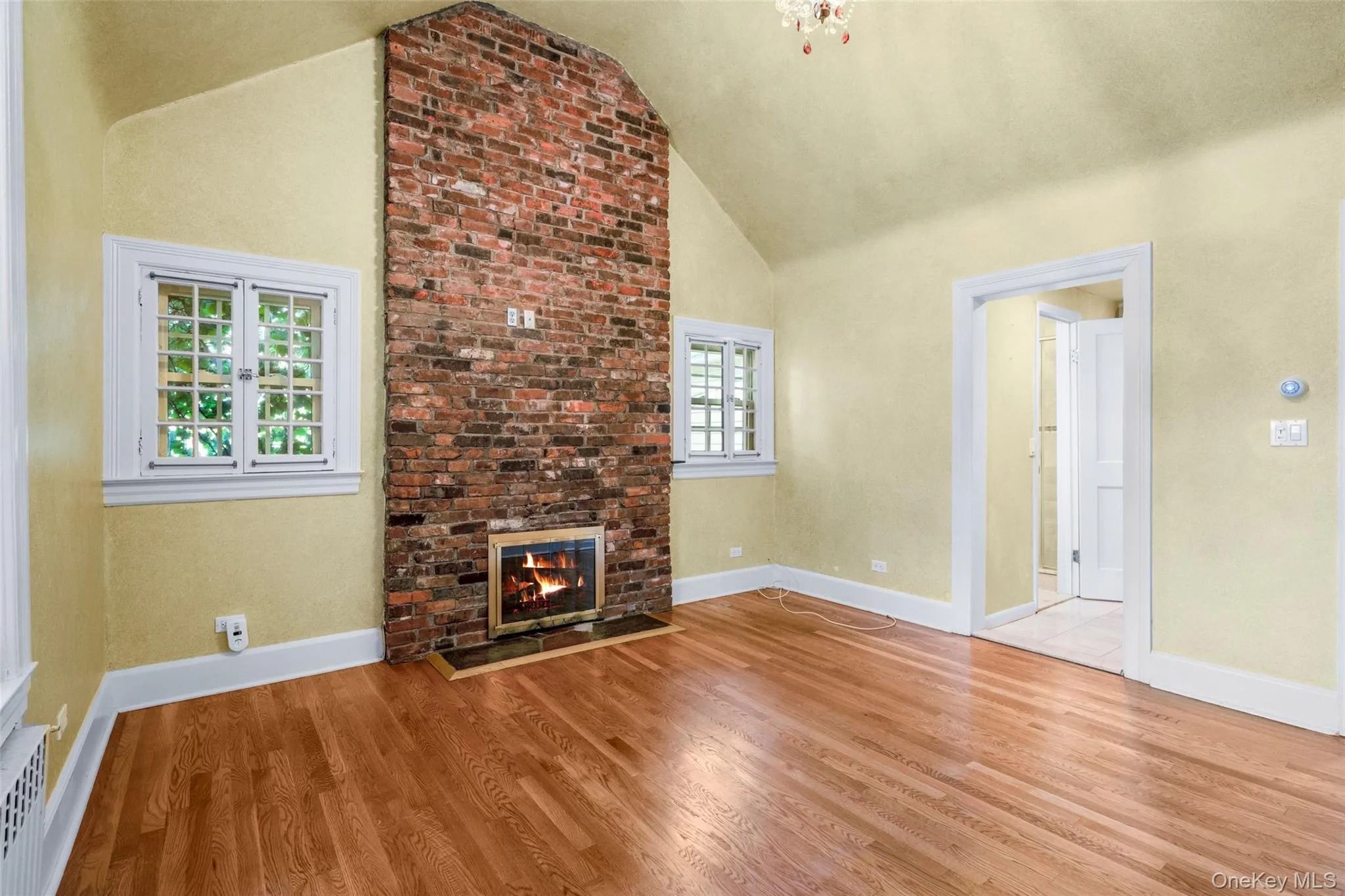 Unfurnished living room with a fireplace, wood finished floors, and high vaulted ceiling Unfurnished living room with a fireplace, wood finished floors, and high vaulted ceiling