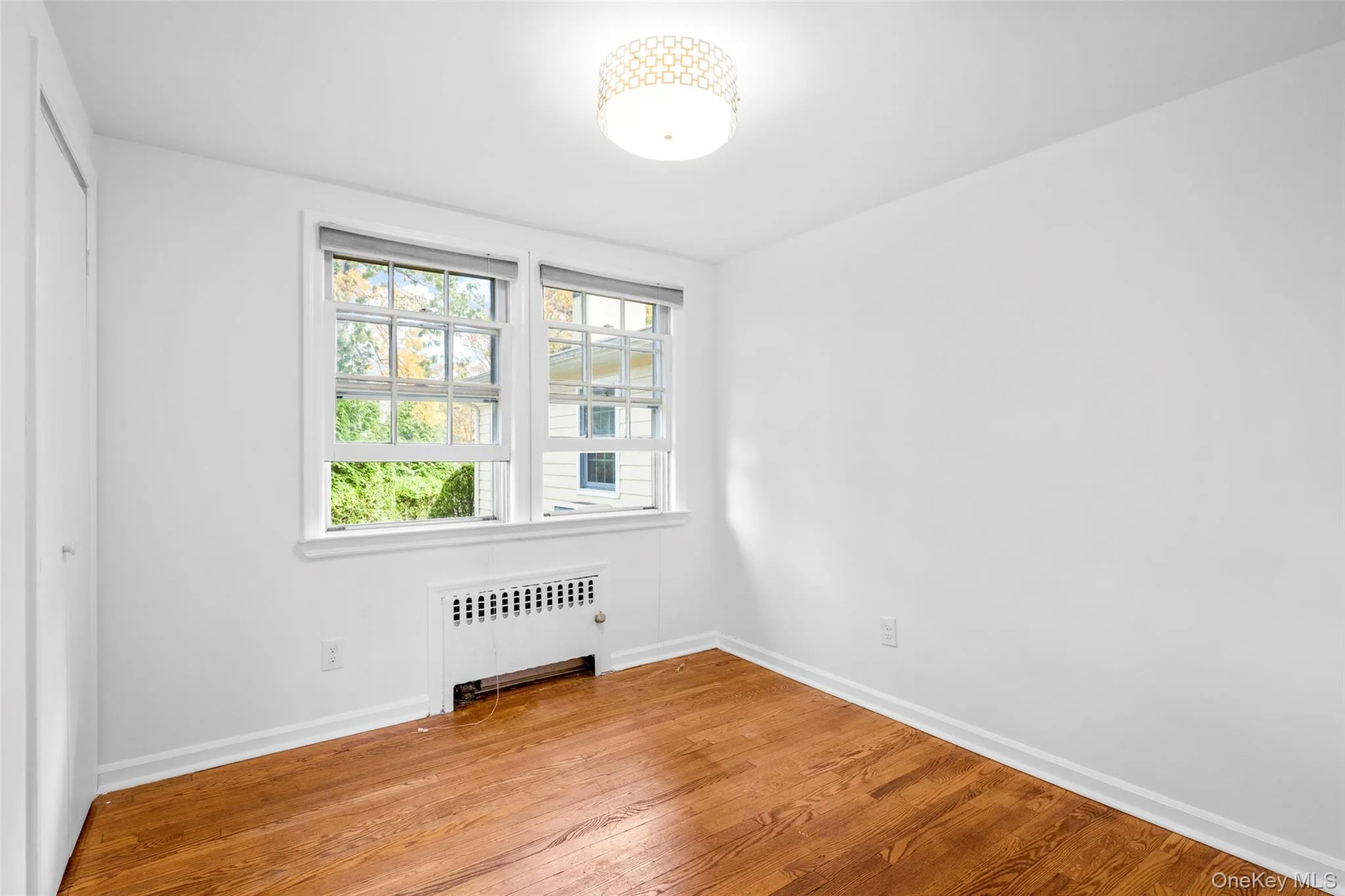 Unfurnished room with radiator and wood finished floors Unfurnished room with radiator and wood finished floors