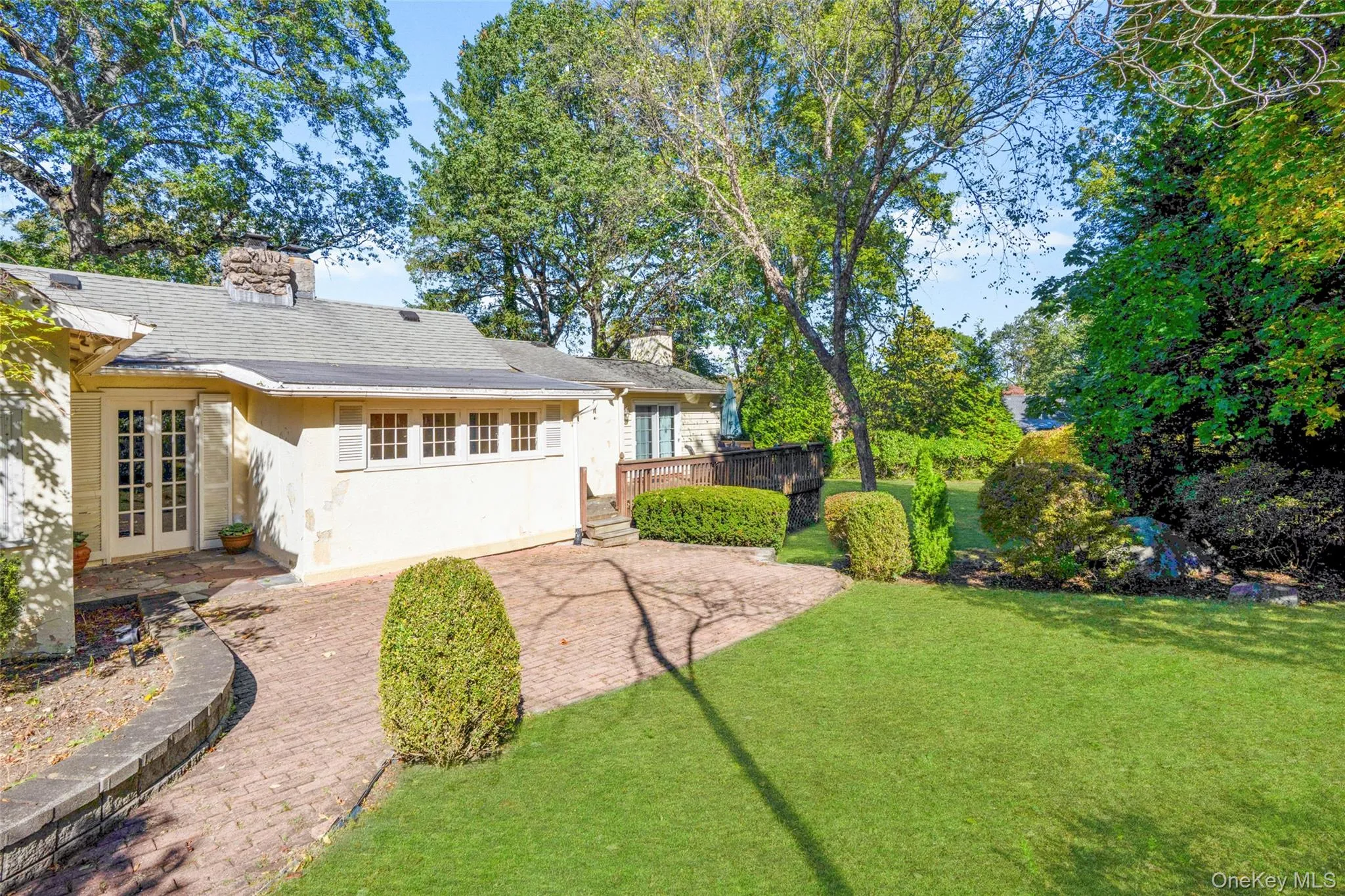 Back of house featuring french doors, a chimney, a yard, and stucco siding Back of house featuring french doors, a chimney, a yard, and stucco siding