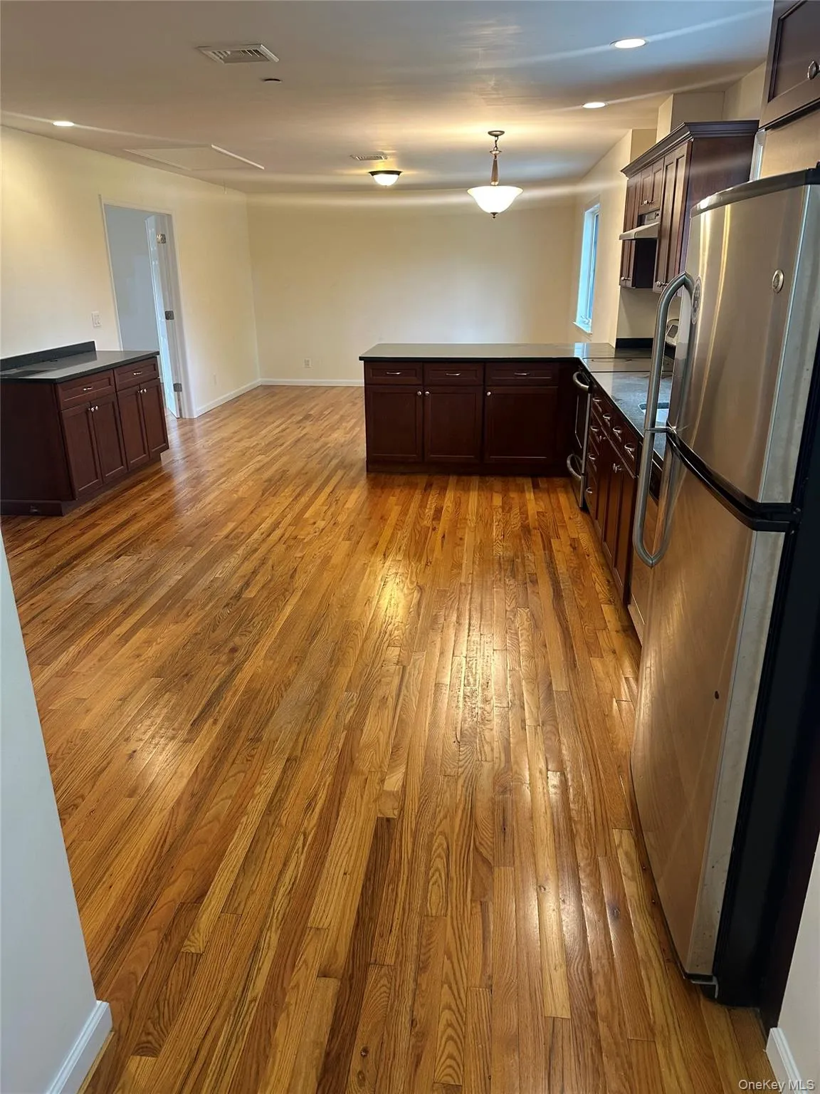 Kitchen featuring hardwood floors, decorative light fixtures, and a peninsula. Living & dining area. Kitchen featuring hardwood floors, decorative light fixtures, and a peninsula. Living & dining area.