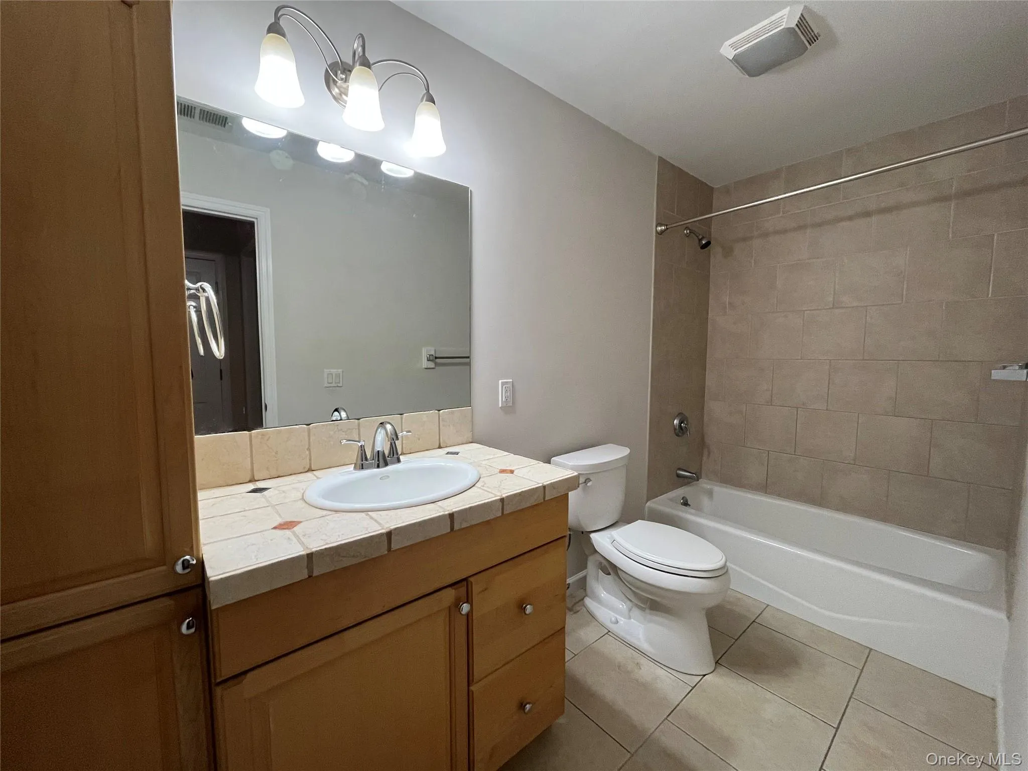 Bathroom featuring vanity, light tile patterned flooring, and shower / bathtub combination Bathroom featuring vanity, light tile patterned flooring, and shower / bathtub combination