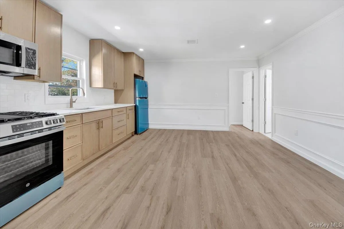 Kitchen with light brown cabinets, appliances with stainless steel finishes, light countertops, light wood-style flooring, and recessed lighting Kitchen with light brown cabinets, appliances with stainless steel finishes, light countertops, light wood-style flooring, and recessed lighting