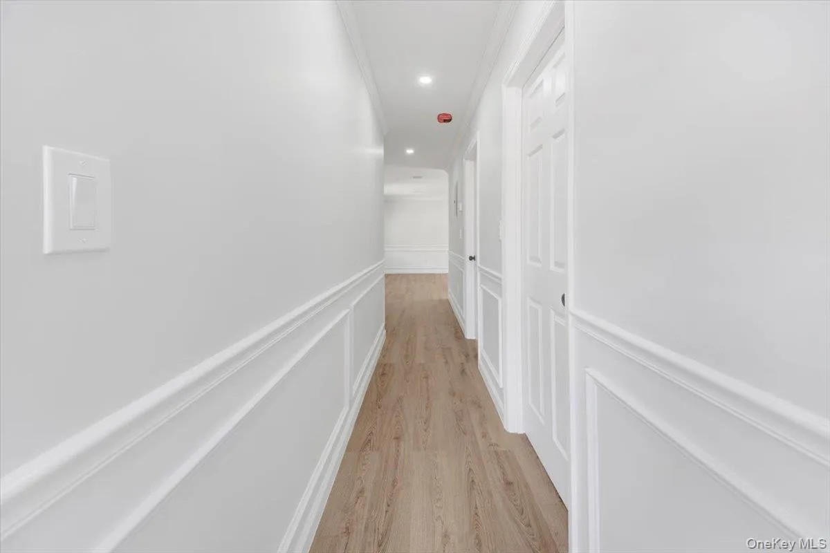 Corridor featuring a decorative wall, a wainscoted wall, light wood-style floors, ornamental molding, and recessed lighting Corridor featuring a decorative wall, a wainscoted wall, light wood-style floors, ornamental molding, and recessed lighting