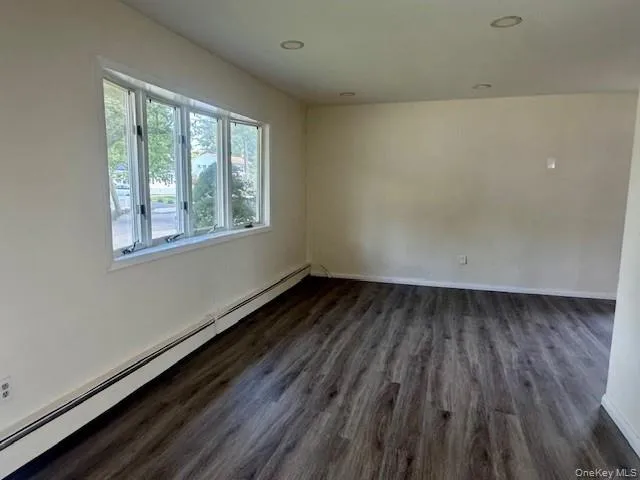 Empty room featuring a baseboard heating unit and dark wood-type flooring Empty room featuring a baseboard heating unit and dark wood-type flooring
