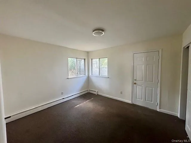 Empty room featuring a baseboard heating unit and carpet flooring Empty room featuring a baseboard heating unit and carpet flooring