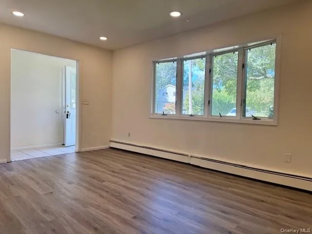 Empty room with a baseboard radiator, wood finished floors, and recessed lighting Empty room with a baseboard radiator, wood finished floors, and recessed lighting