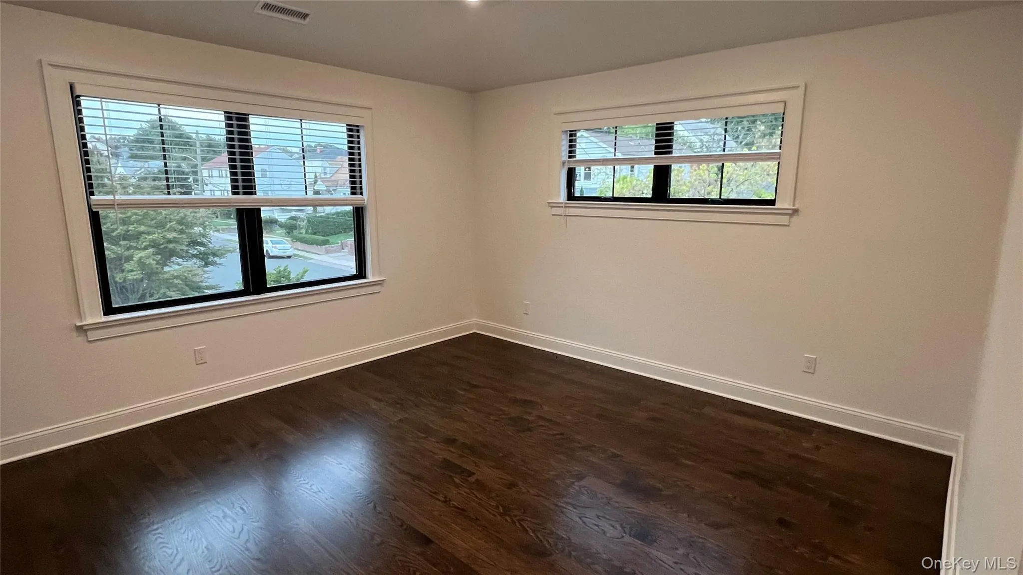 Spare room featuring dark wood-style flooring and baseboards Spare room featuring dark wood-style flooring and baseboards