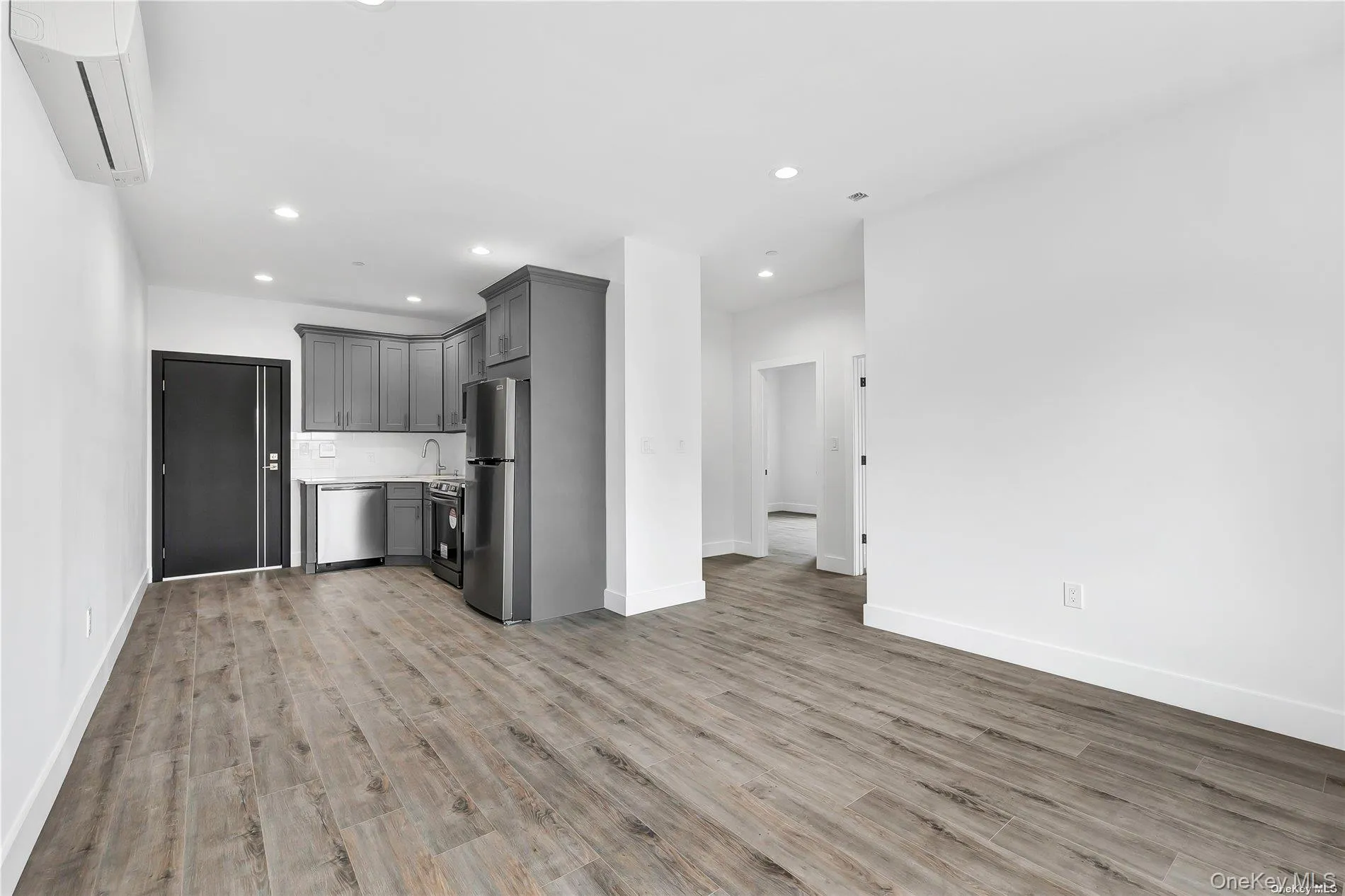 Kitchen with gray cabinetry, recessed lighting, a wall mounted air conditioner, stainless steel appliances, and light countertops Kitchen with gray cabinetry, recessed lighting, a wall mounted air conditioner, stainless steel appliances, and light countertops