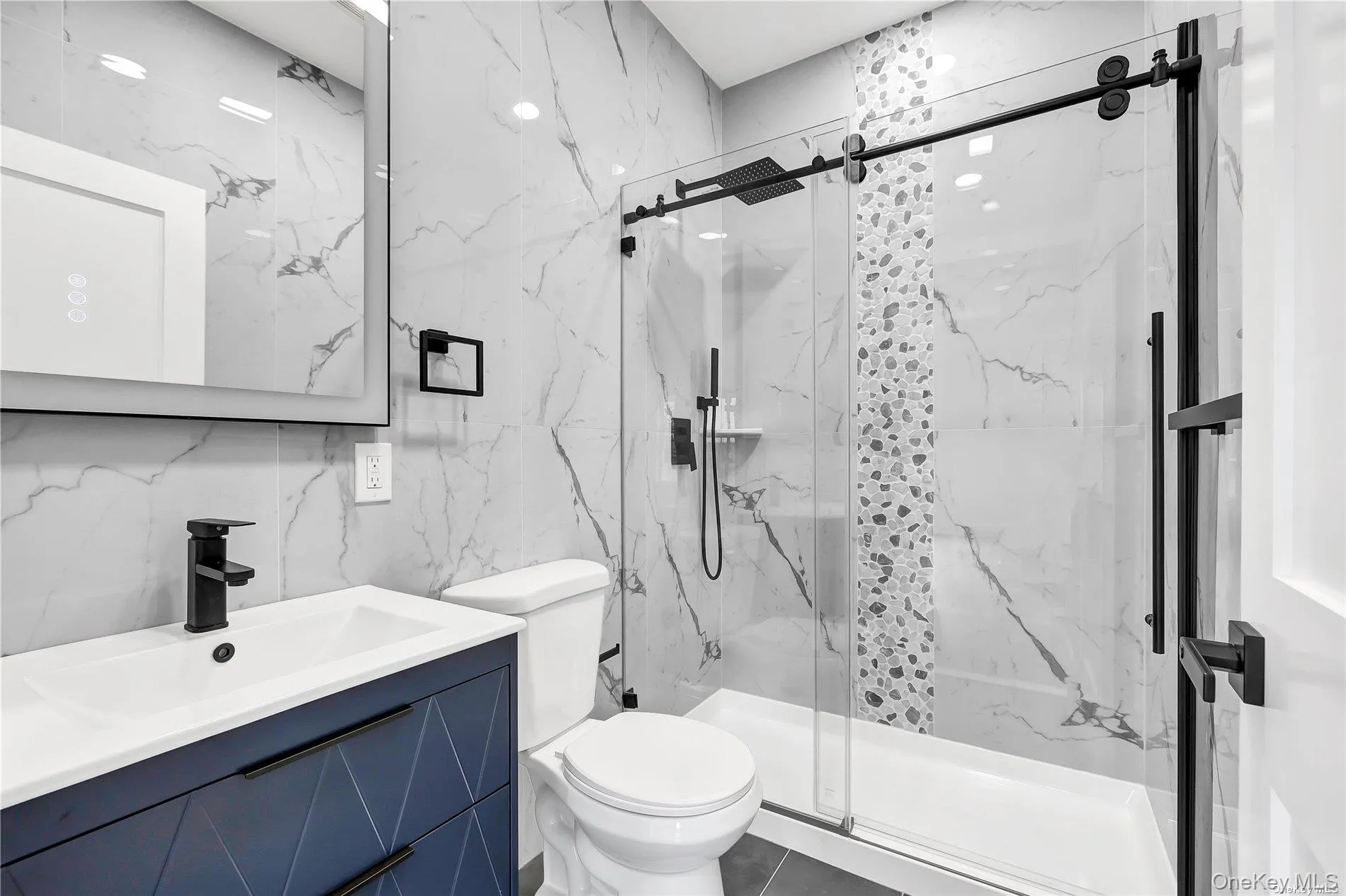 Bathroom featuring vanity, tile walls, a marble finish shower, and stone wall Bathroom featuring vanity, tile walls, a marble finish shower, and stone wall