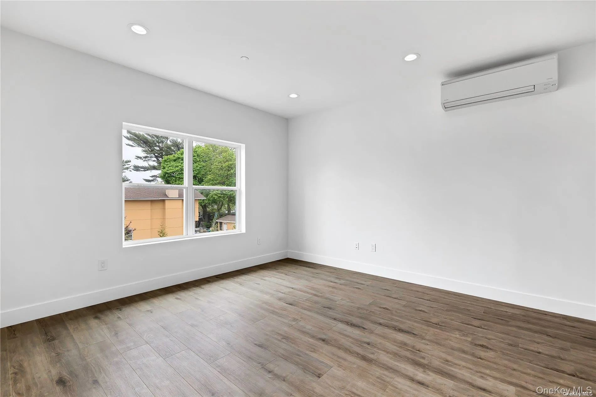 Empty room with recessed lighting, wood finished floors, and an AC wall unit Empty room with recessed lighting, wood finished floors, and an AC wall unit