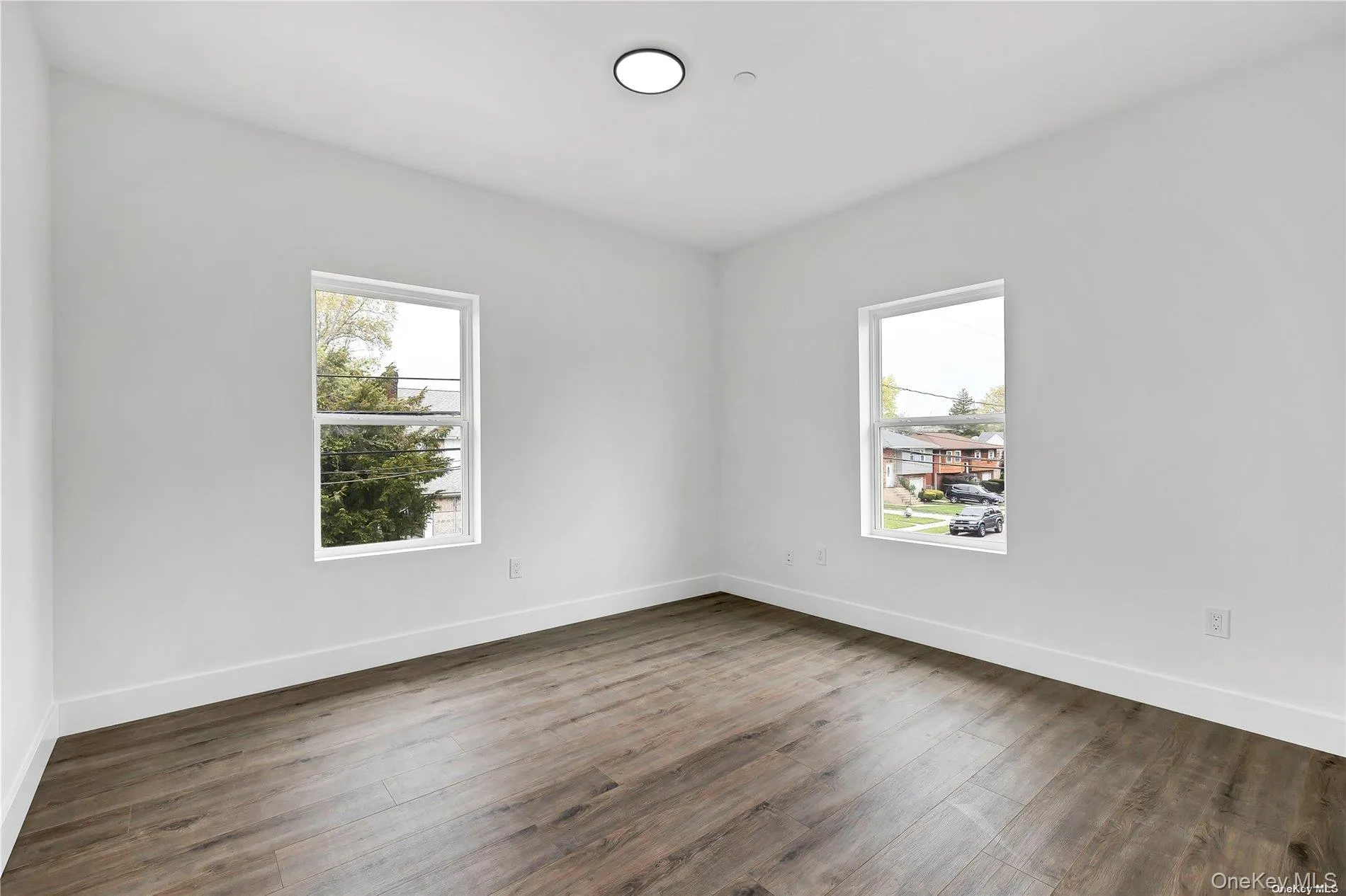 Spare room featuring healthy amount of natural light and dark wood finished floors Spare room featuring healthy amount of natural light and dark wood finished floors