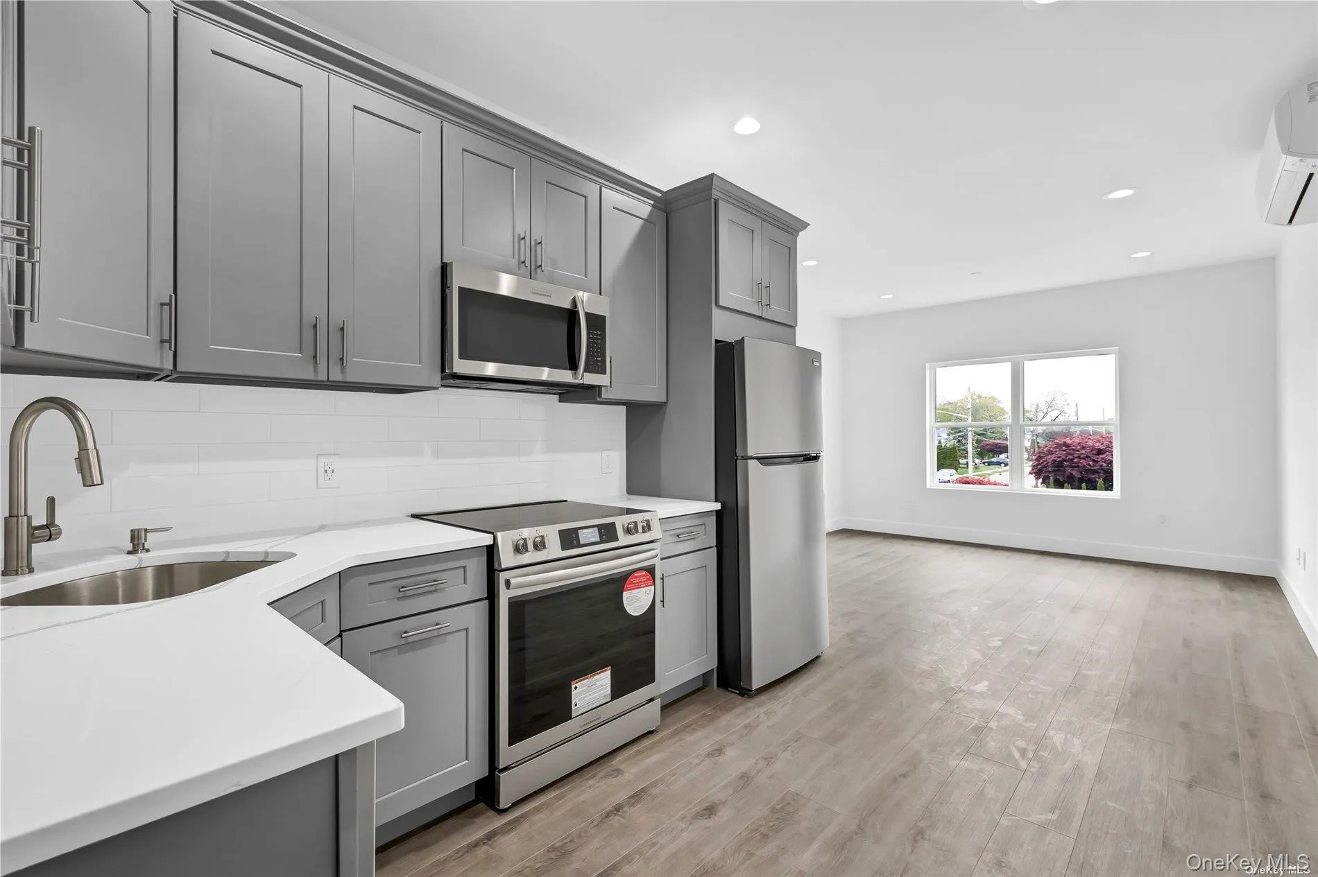 Kitchen featuring gray cabinets, appliances with stainless steel finishes, tasteful backsplash, recessed lighting, and light wood-style flooring Kitchen featuring gray cabinets, appliances with stainless steel finishes, tasteful backsplash, recessed lighting, and light wood-style flooring