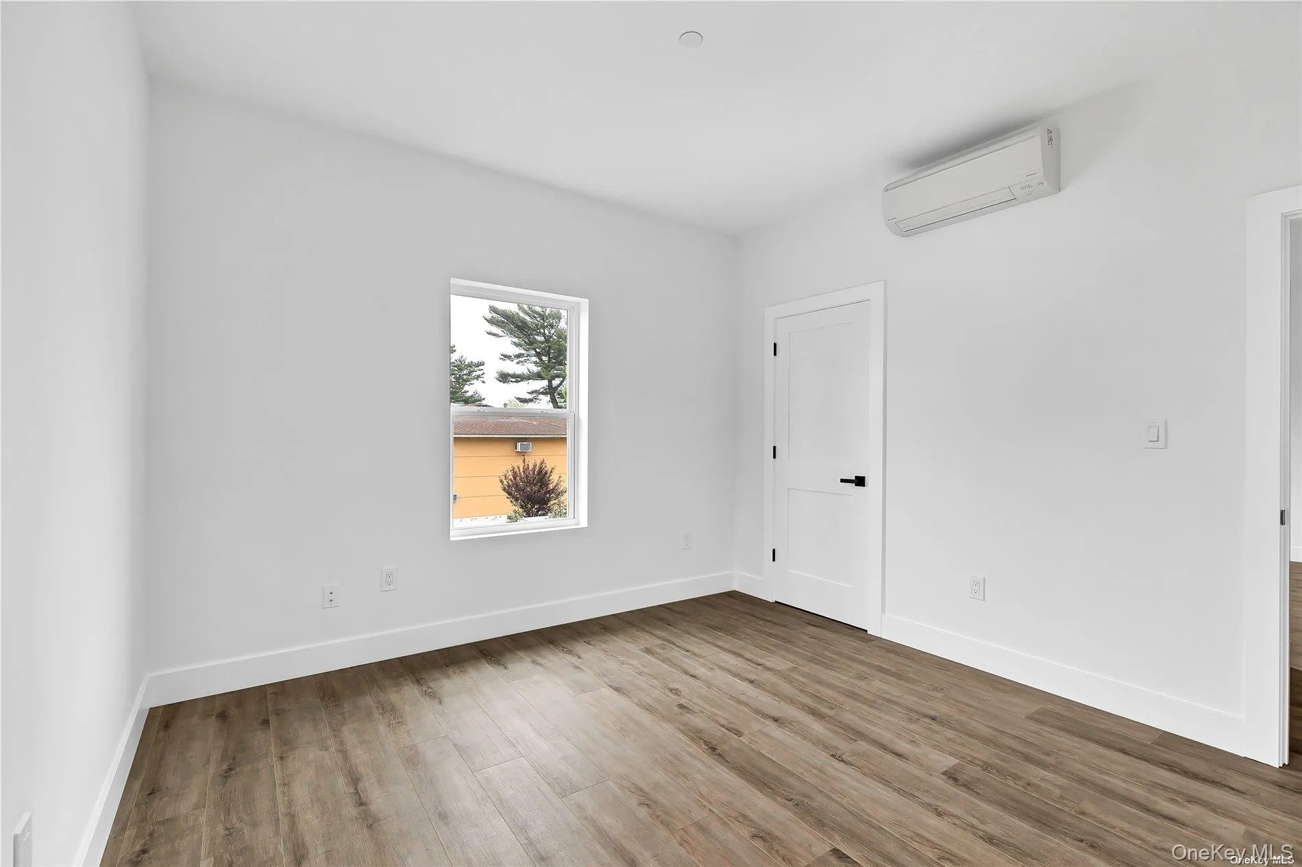 Unfurnished room with wood finished floors and an AC wall unit Unfurnished room with wood finished floors and an AC wall unit