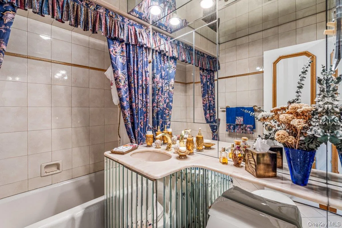 Full bathroom with a bathtub, vanity, and tile walls Full bathroom with a bathtub, vanity, and tile walls