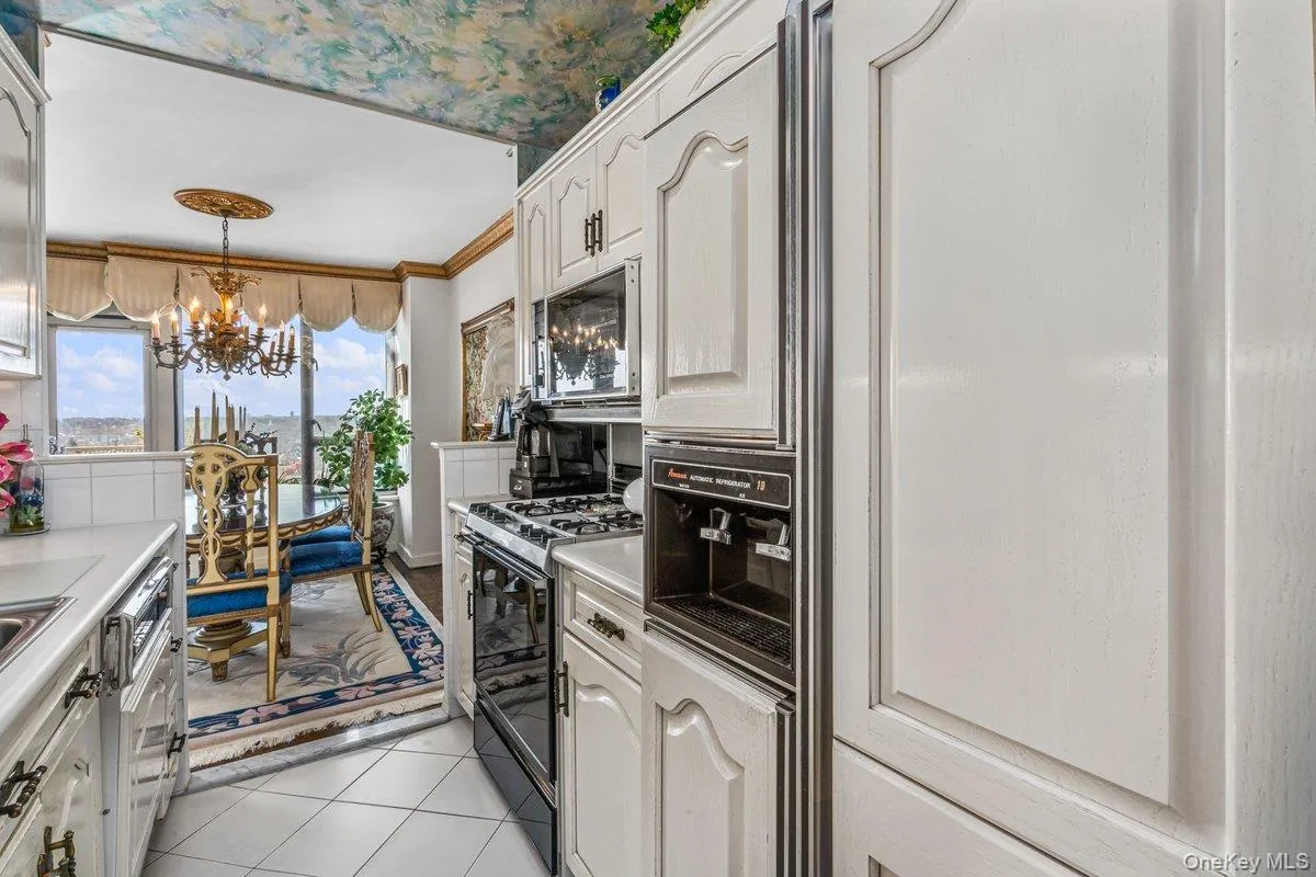 Kitchen featuring decorative light fixtures, light tile patterned flooring, gas stove, a chandelier, and light countertops Kitchen featuring decorative light fixtures, light tile patterned flooring, gas stove, a chandelier, and light countertops