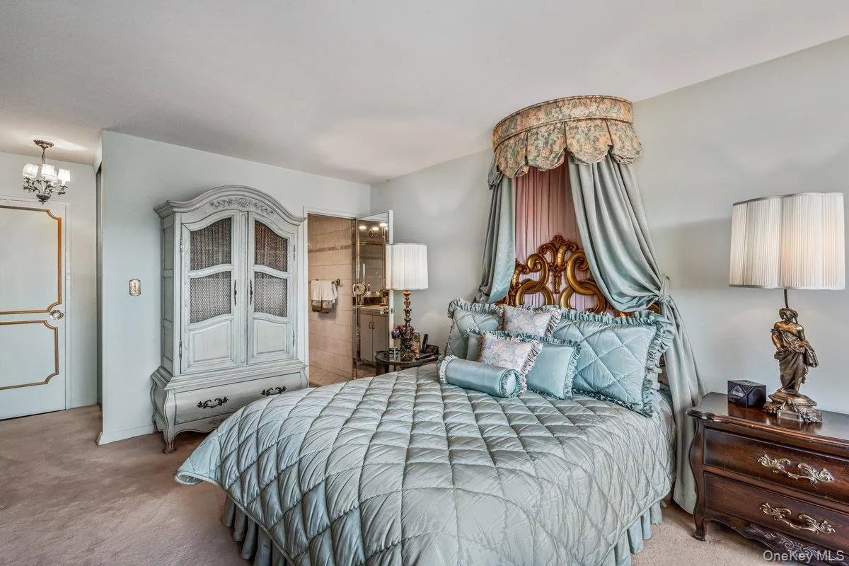 Bedroom featuring carpet, connected bathroom, and a chandelier Bedroom featuring carpet, connected bathroom, and a chandelier