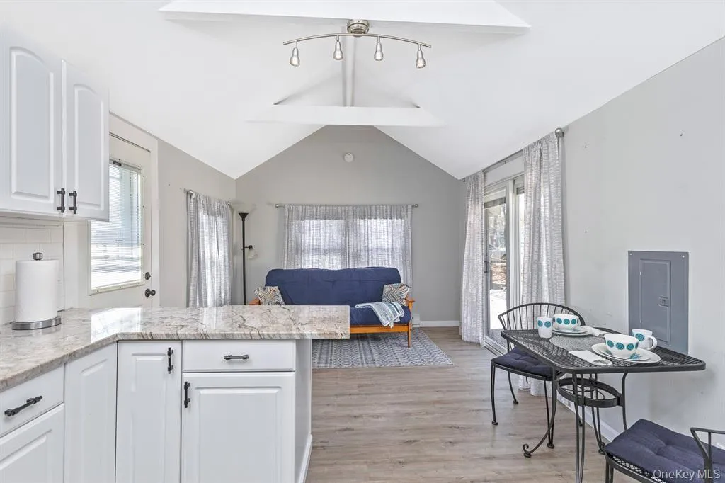 Kitchen with light stone countertops, white cabinetry, light wood finished floors, a peninsula, and open floor plan Kitchen with light stone countertops, white cabinetry, light wood finished floors, a peninsula, and open floor plan