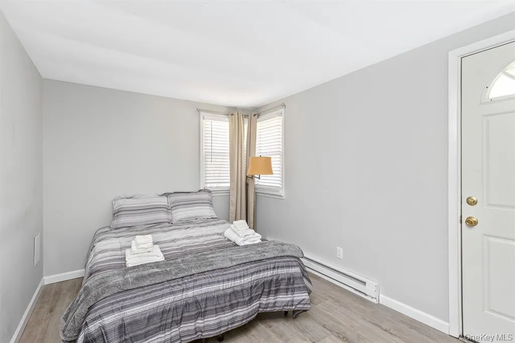 Bedroom with a baseboard heating unit, multiple windows, and light wood-style flooring Bedroom with a baseboard heating unit, multiple windows, and light wood-style flooring