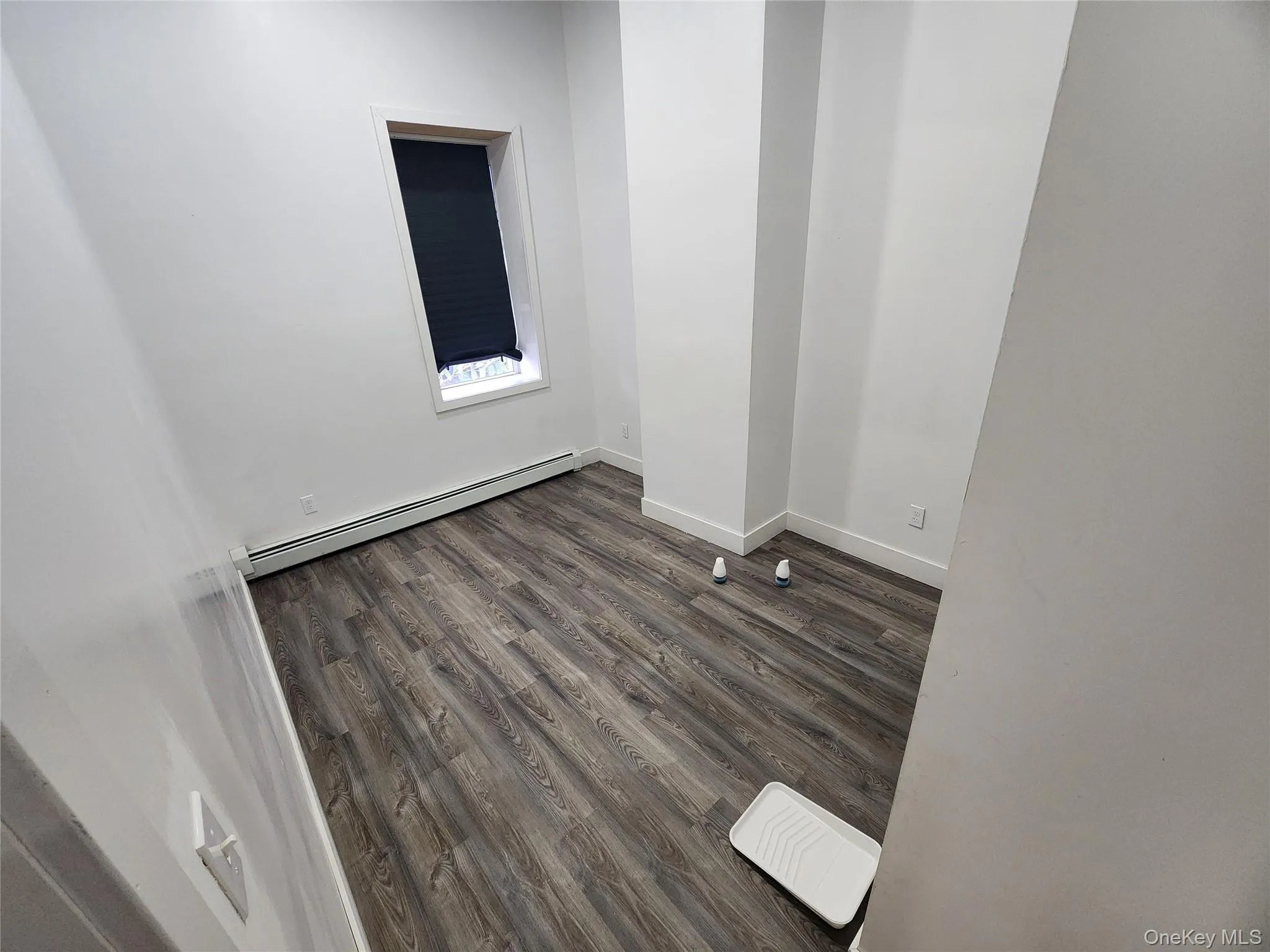 Empty room with a baseboard heating unit and dark wood finished floors Empty room with a baseboard heating unit and dark wood finished floors