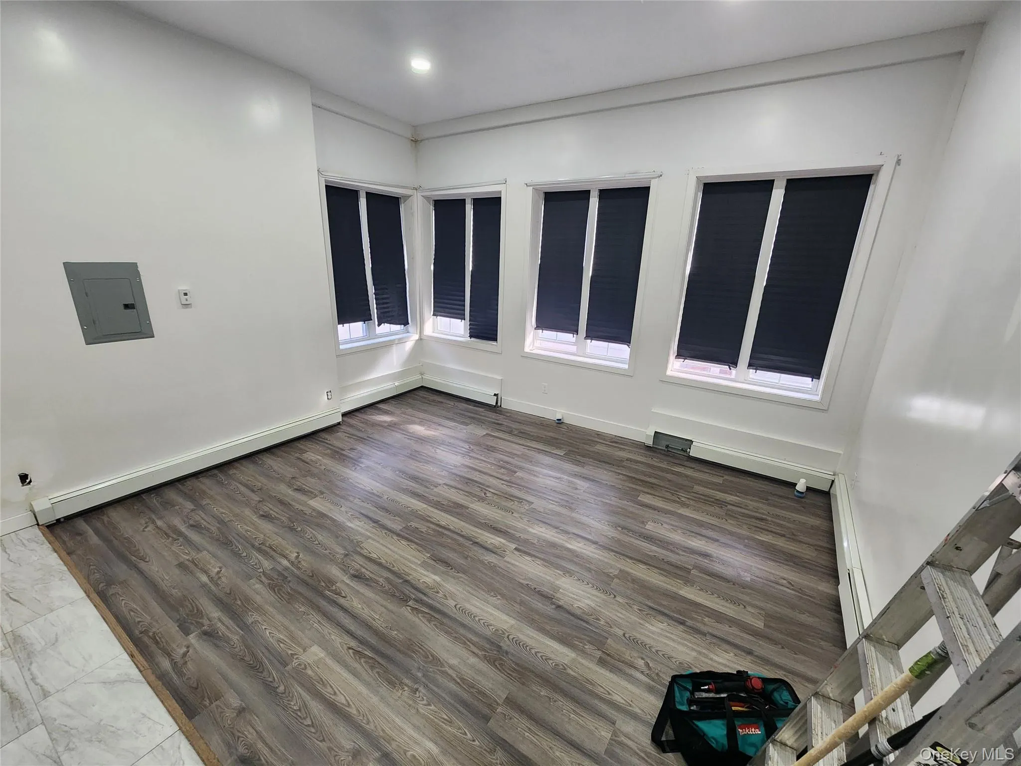 Unfurnished room with electric panel, wood finished floors, a baseboard heating unit, and recessed lighting Unfurnished room with electric panel, wood finished floors, a baseboard heating unit, and recessed lighting