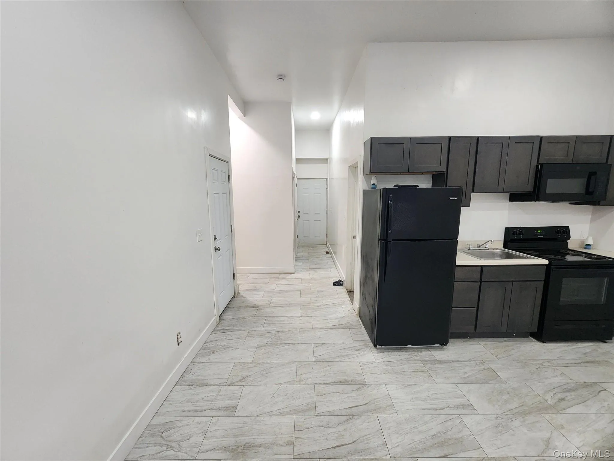 Kitchen with black appliances, light countertops, and dark cabinets Kitchen with black appliances, light countertops, and dark cabinets